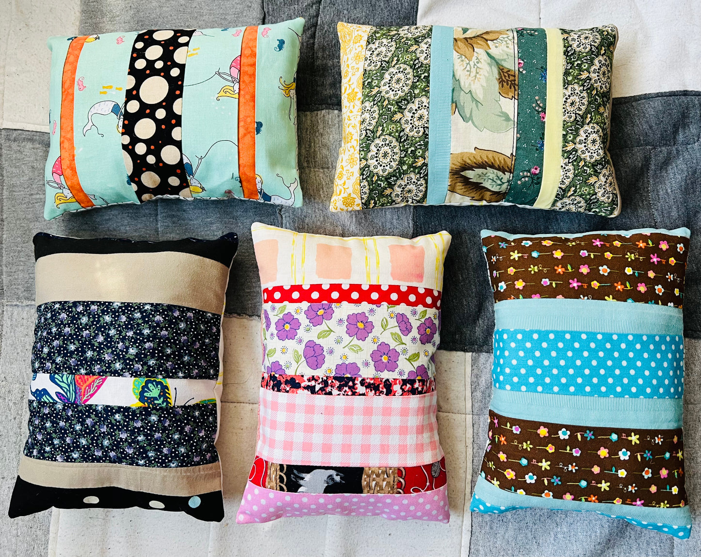 Collection of colorful patchwork pillows on a textured surface, American Girl doll sized