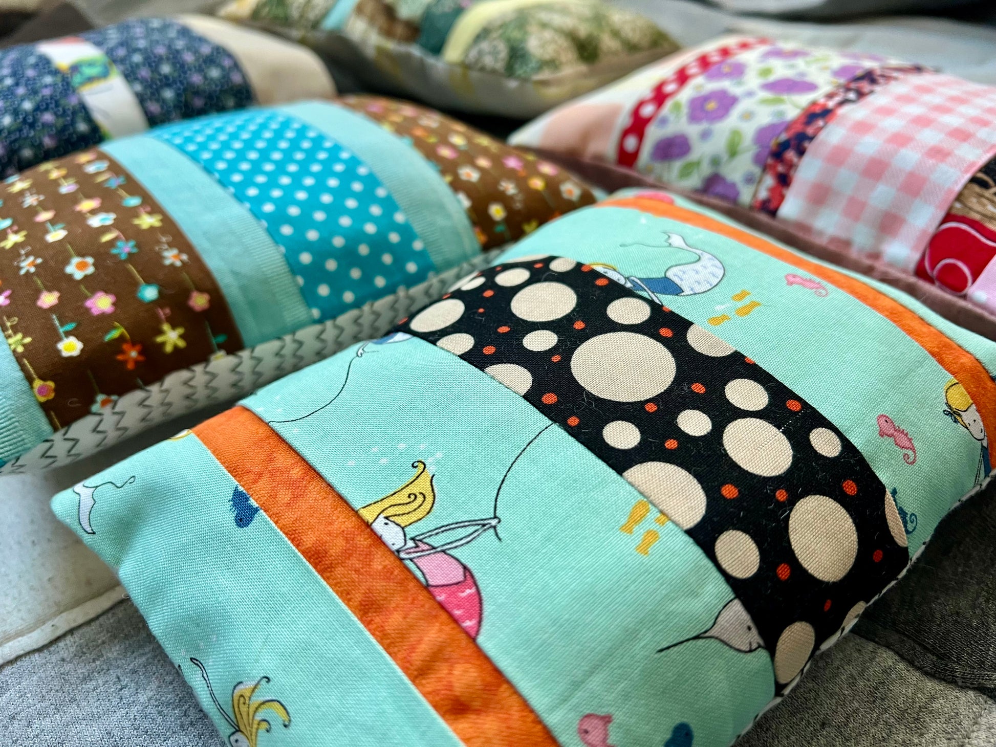 Colorful patchwork pillows with various patterns on a soft surface.