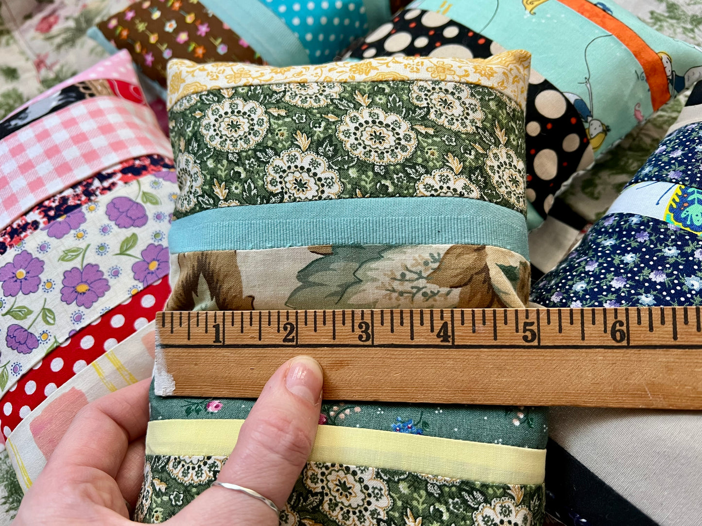 American Girl doll pillow, made from scrappy fabric strips, with a ruler at the width that says 5 inches.