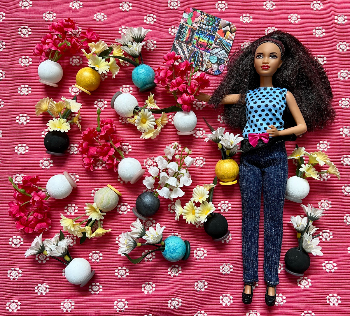 Barbie doll with flowers and accessories on a pink floral-patterned background