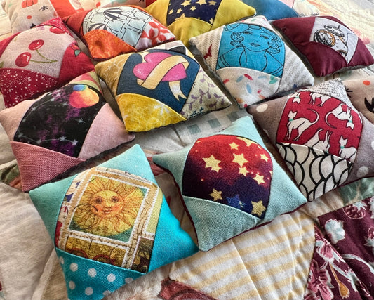 Collection of colorful patchwork dollhouse pillows with various patterns and designs.