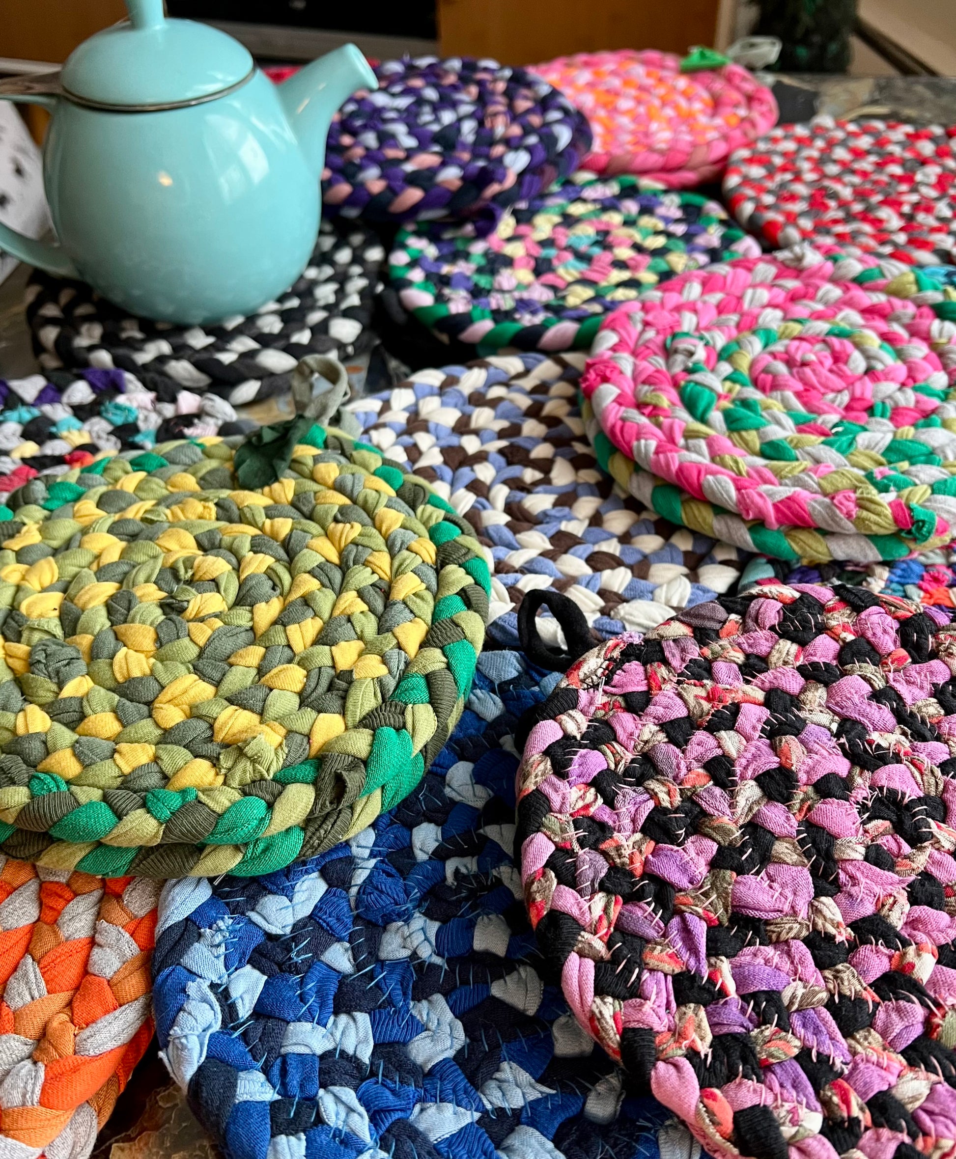 Colorful trivet potholders with a teapot on a wooden surface. 