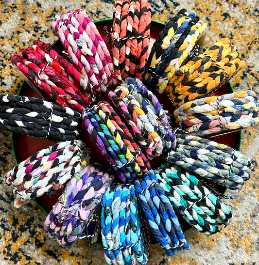 Assorted colorful braided coaster bundles on a textured surface