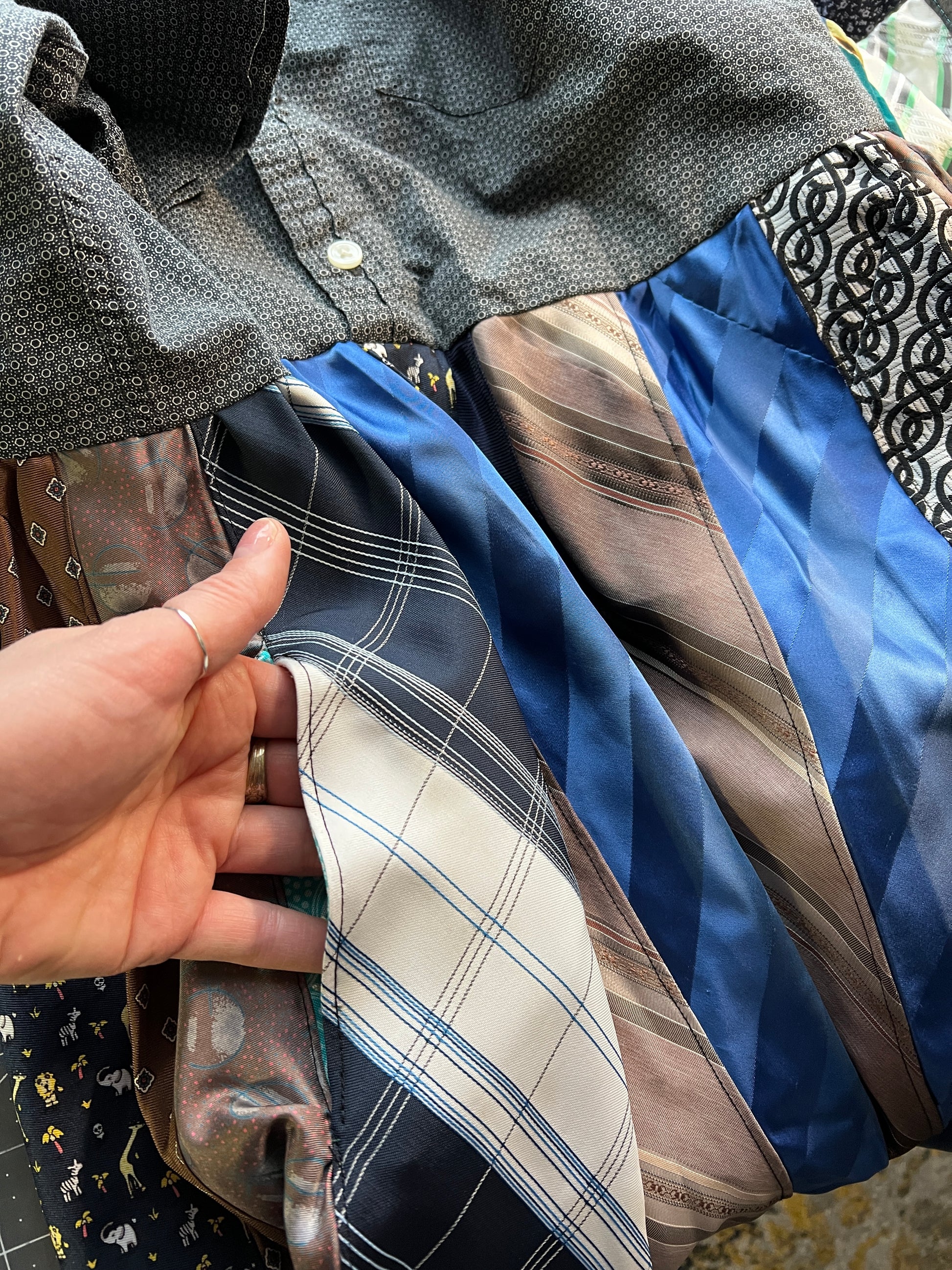 Hand inserted into a pocket, necktie shirtdress detail.