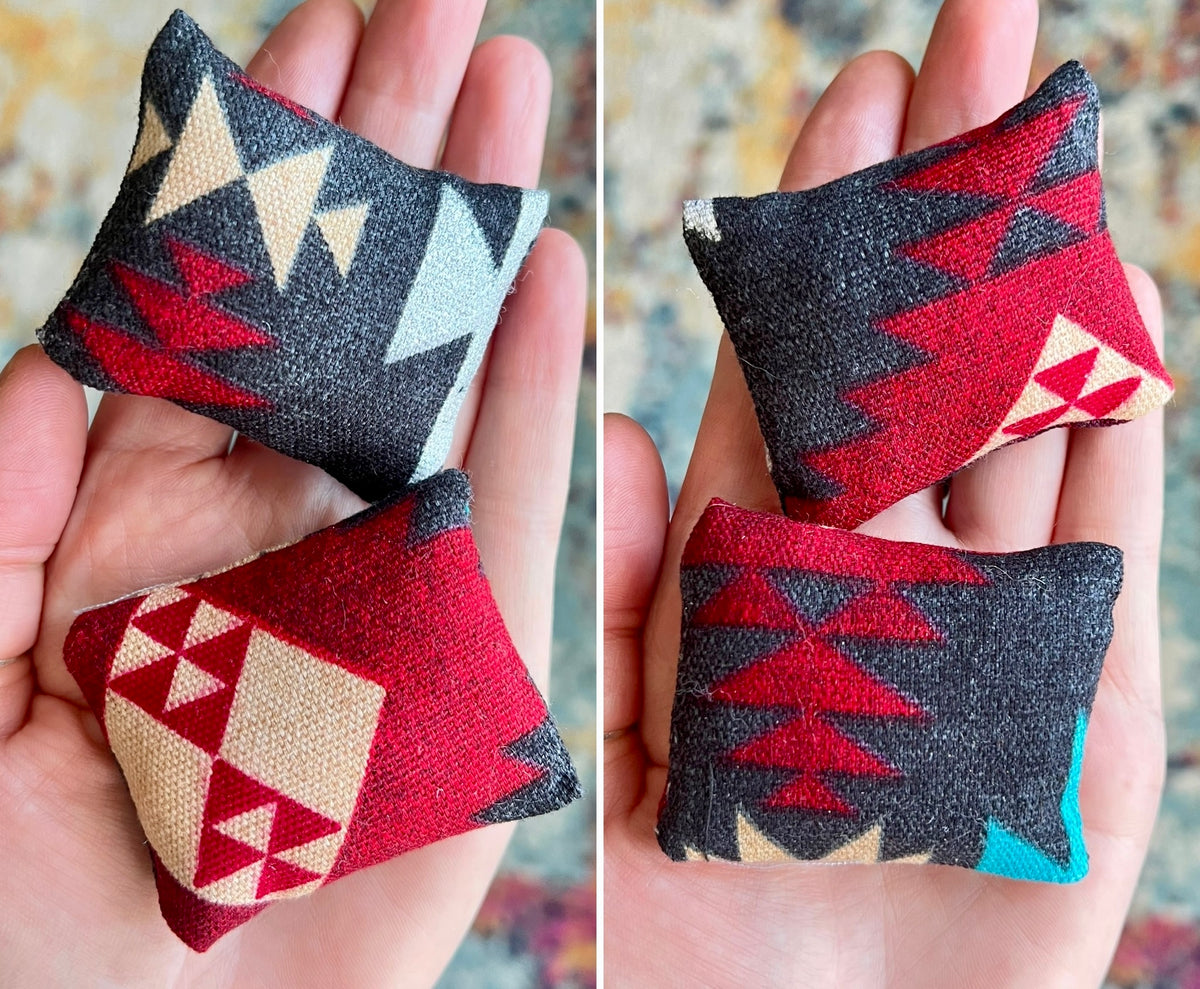 Two small fabric pillows with geometric patterns held in hands against a blurred background.