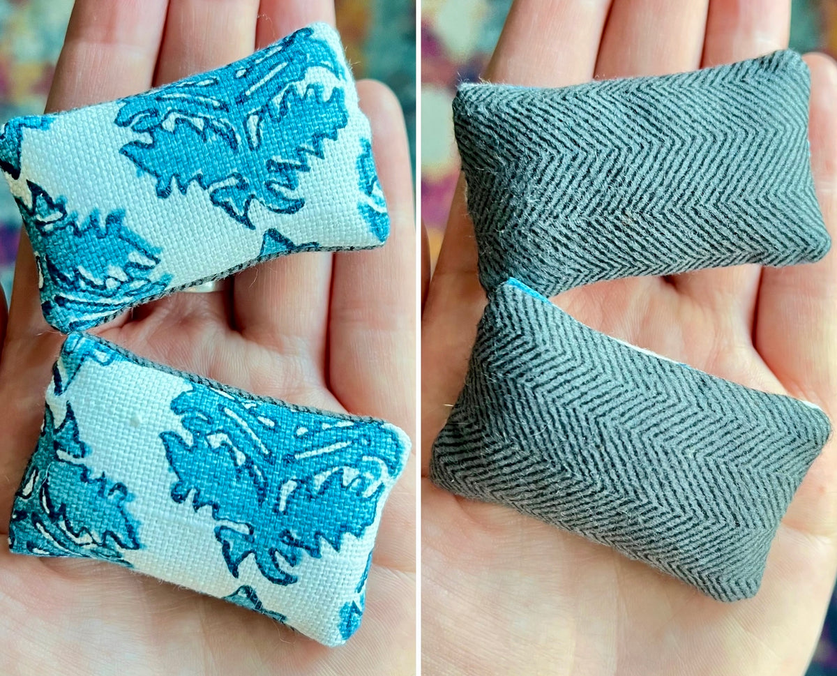 Two fabric doll pillows with different patterns front and back held in hands.