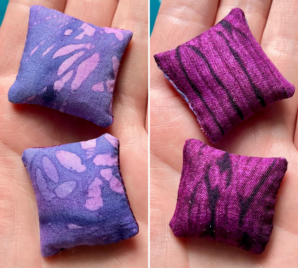 Two small purple fabric pillows with different patterns on a person's palm.