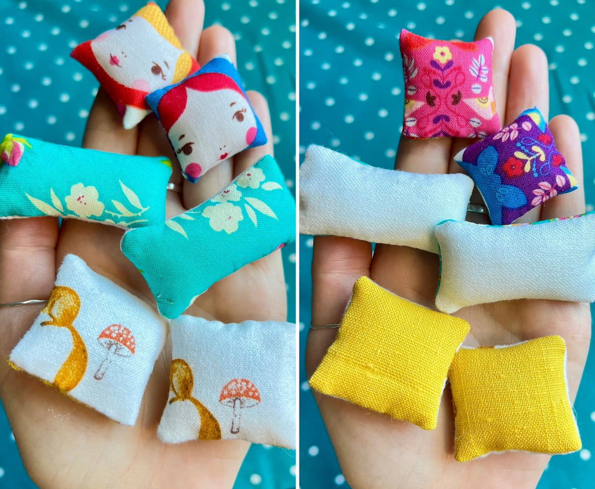 Small fabric pillows in various colors held in hands against a polka dot background.