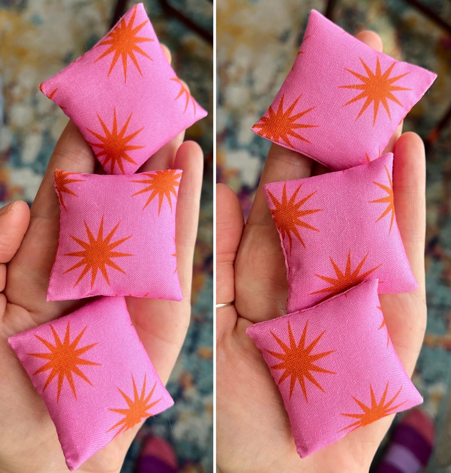 Pink fabric pillows with orange star patterns held in hands against a blurred background