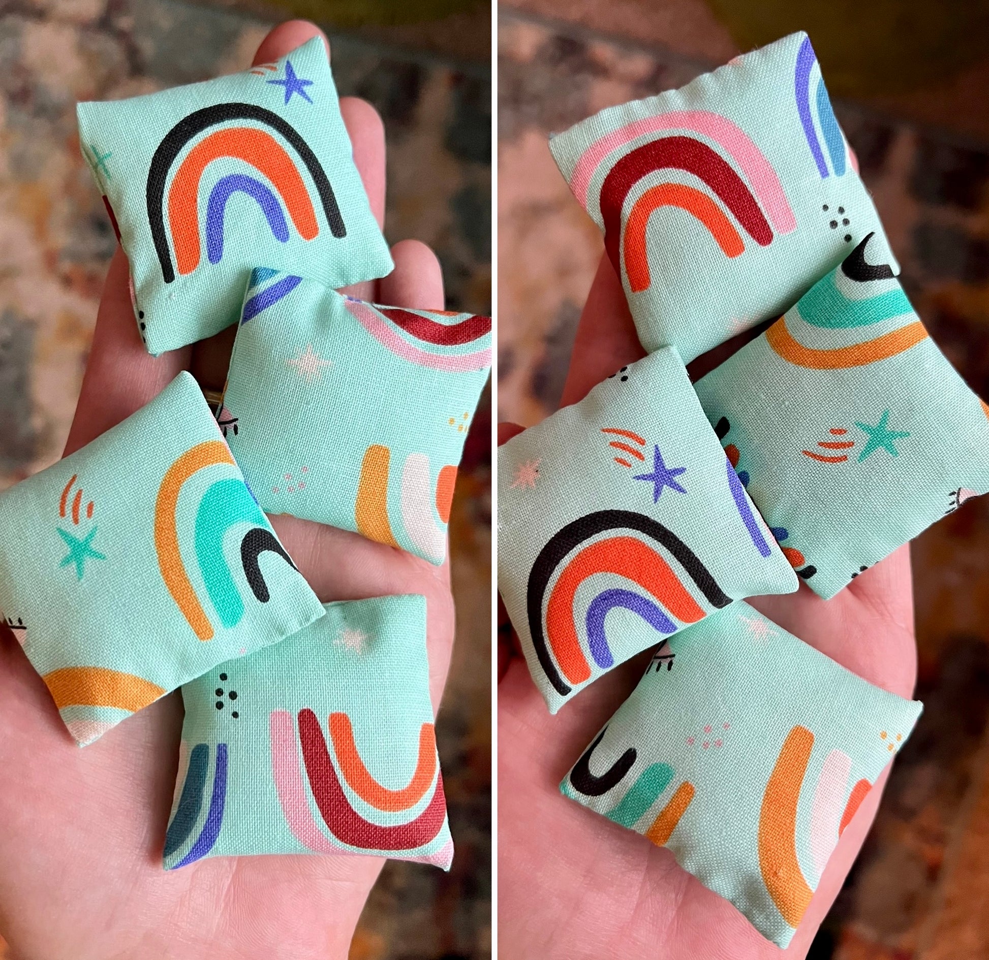 Fabric pillows with rainbow patterns held in a hand against a blurred background