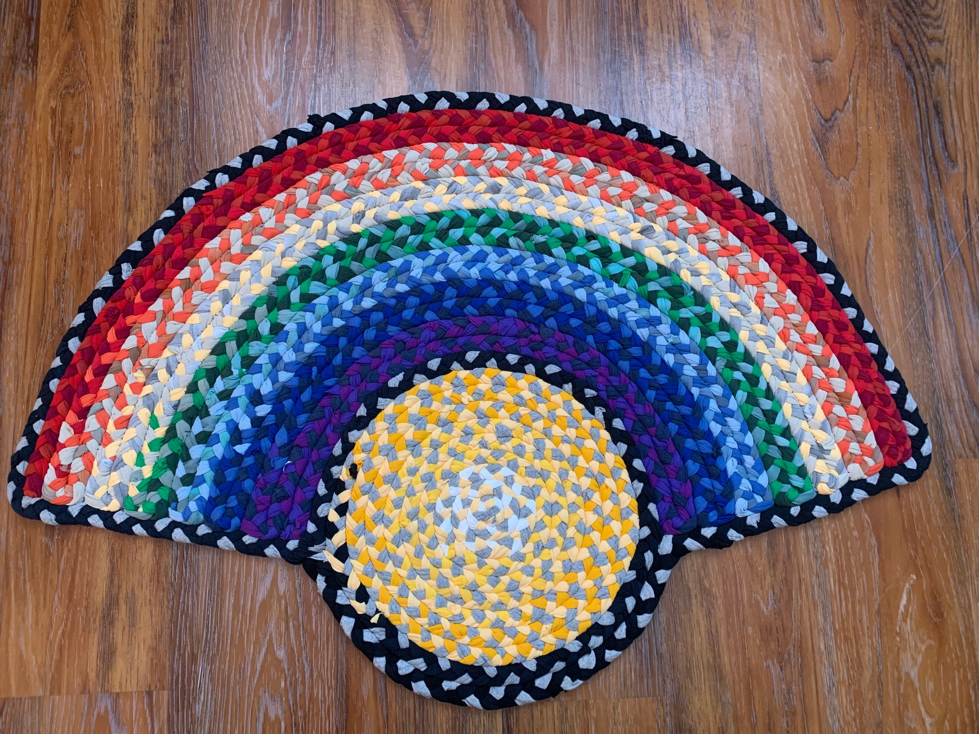 A yellow circle in the middle of the rug denotes the sun, with a rainbow half surrounding the sun, in a typical bow fashion. Red orange yellow green blue indigo and purple.