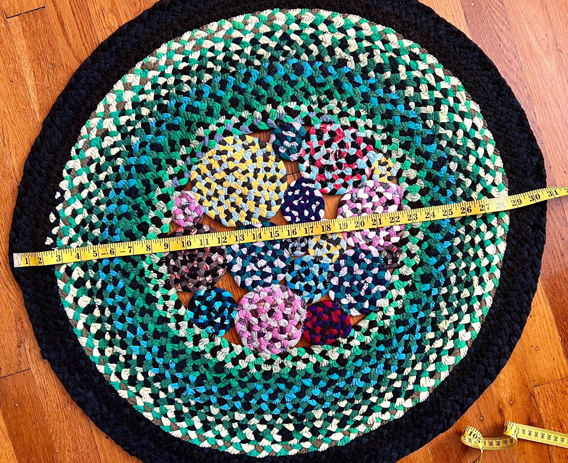 aerial view of green garden rug, with measuring tape across the diameter, showing 30.5 inches