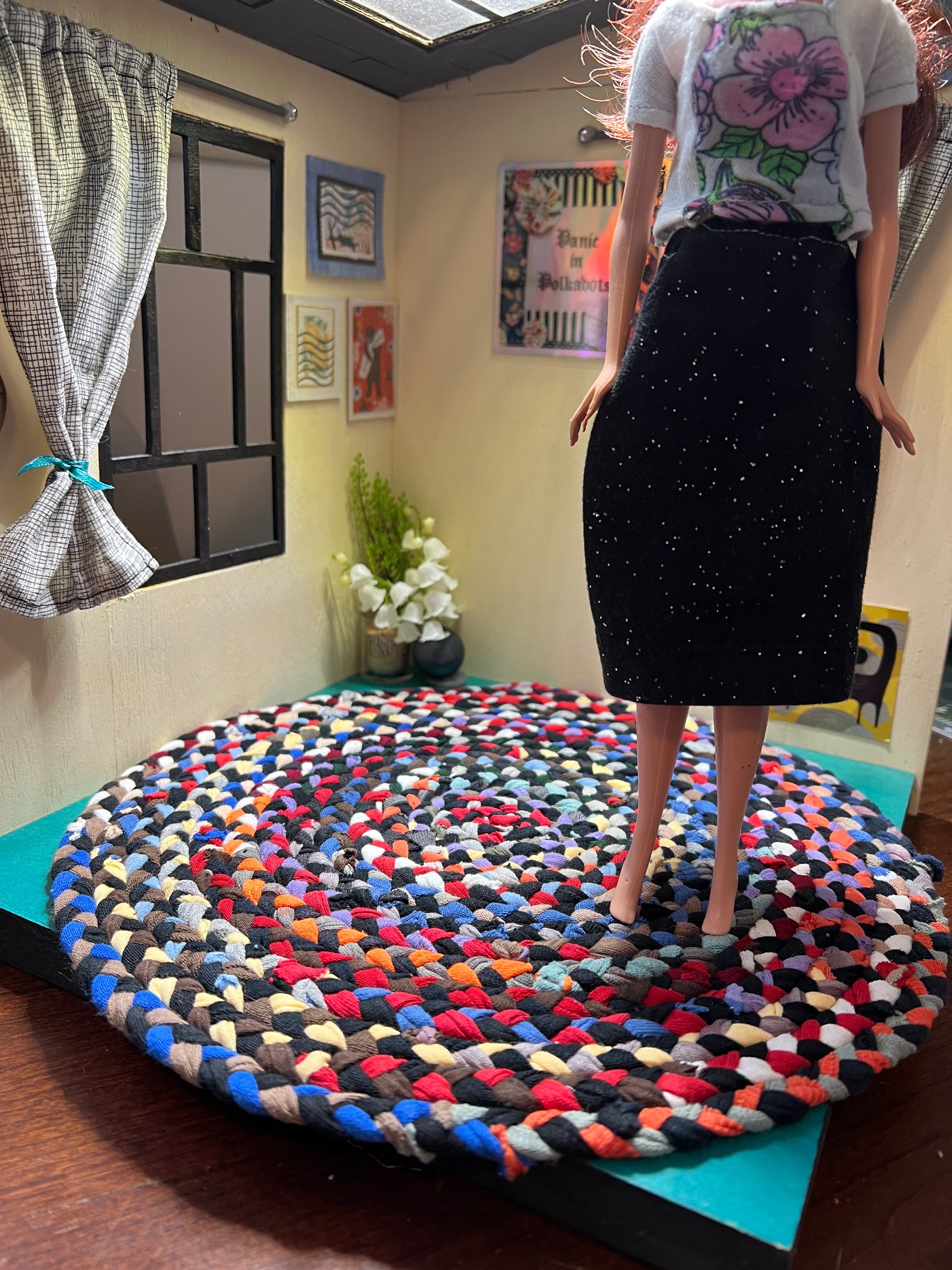 view of miniature rug in a room box, with Barbie standing atop the 11" retro rainbow rug for scale and display ideas