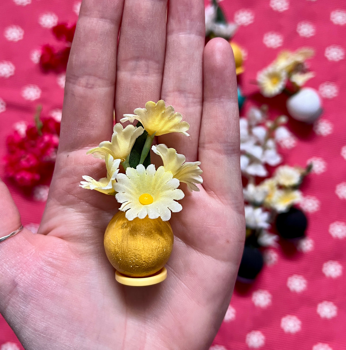 Small yellow flower vase held in a hand with a polka dot background