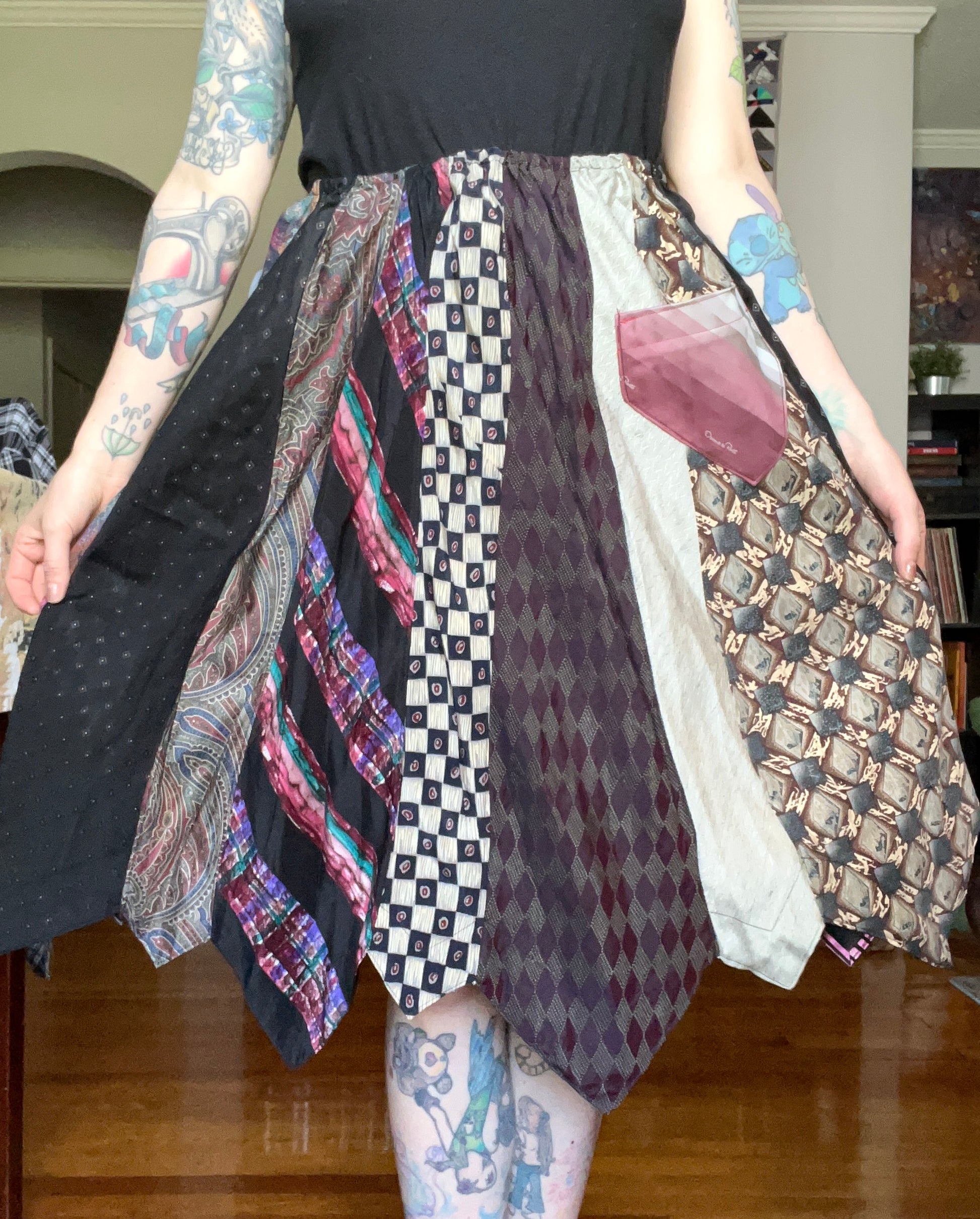 Skirt created out of neckties, as worn by tattooed model. It is held out at the sides to show fullness of the skirt