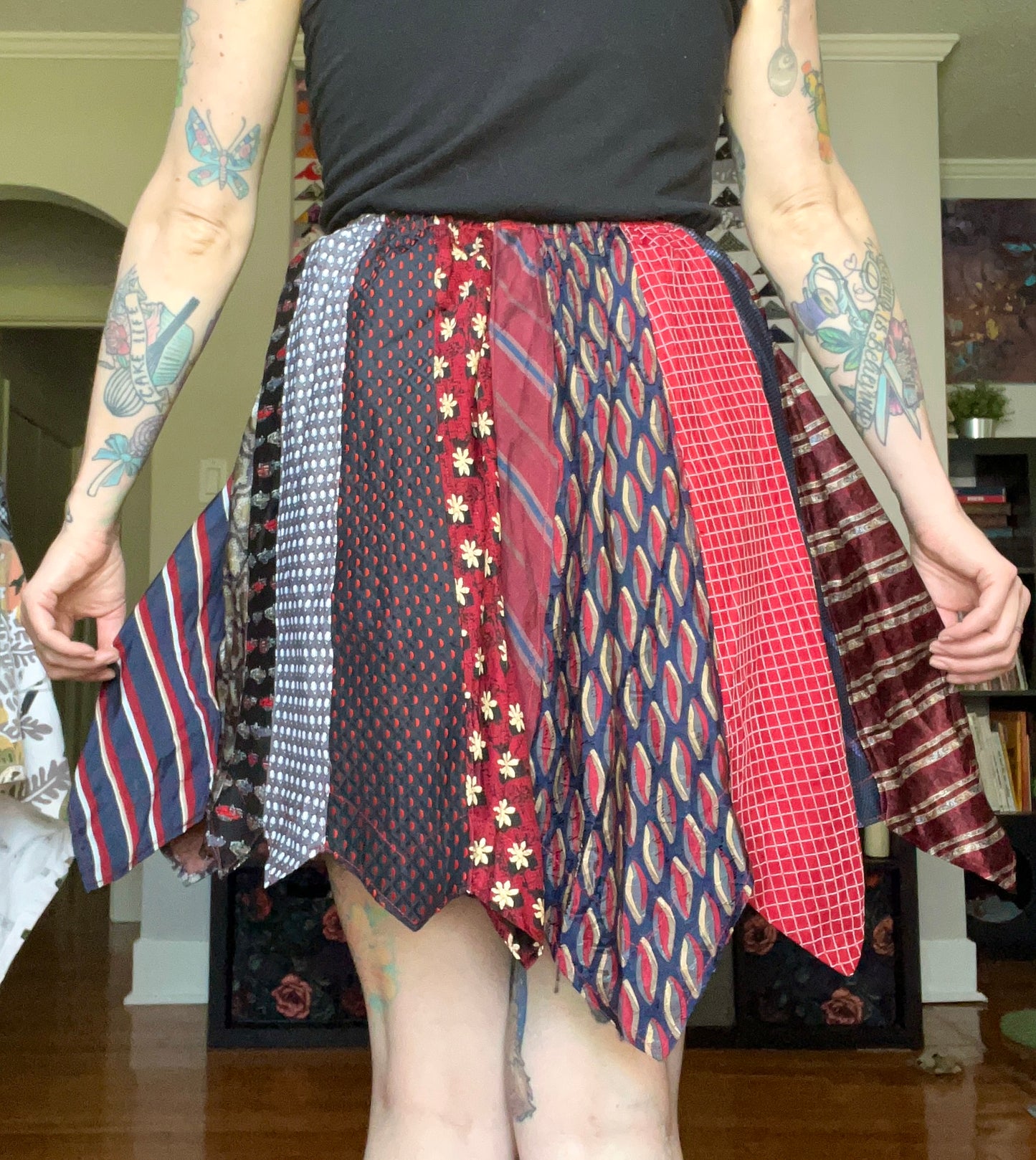 Short red necktie skirt, back view, modeled and held out to the side