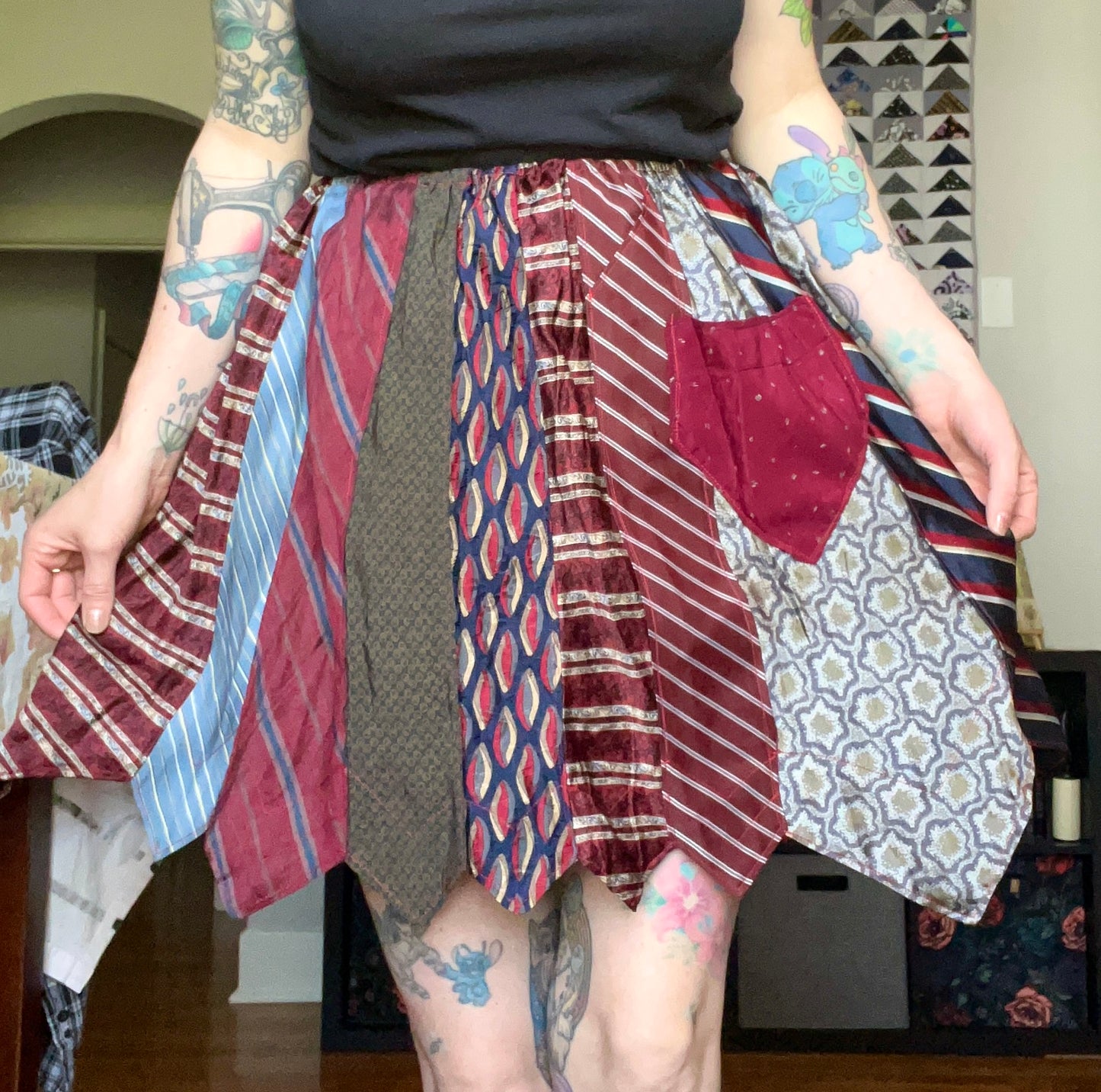 Skirt created out of neckties, as worn by tattooed model. It is held out at the sides to show fullness of the skirt