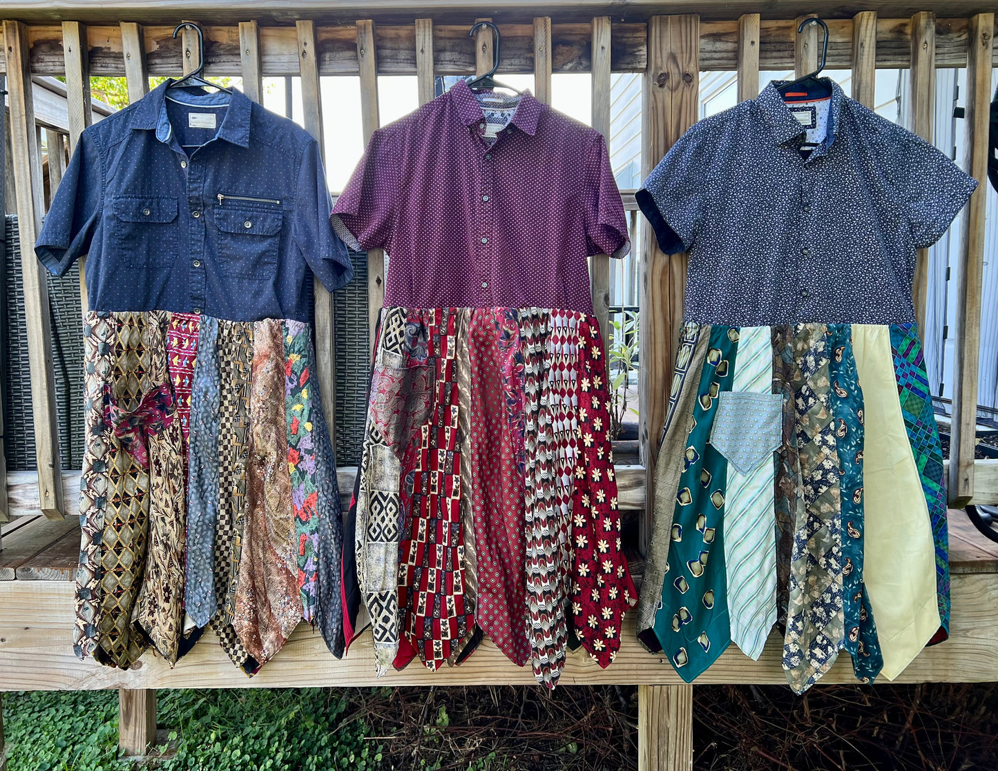 Three different shirtdresses on hangers, along the side of a patio deck.