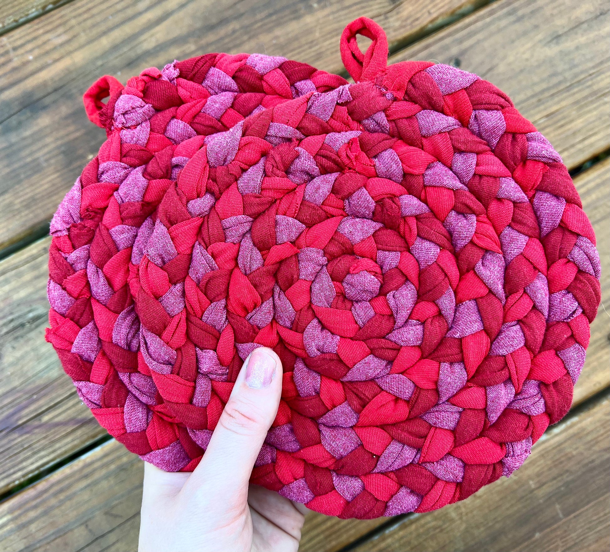 The back of two trivet potholders, held by a hand.