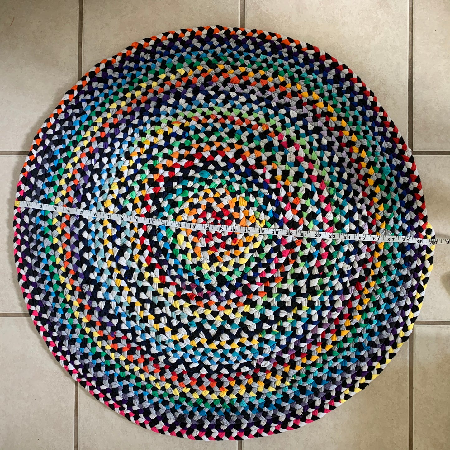 Aerial view, of the top of the rug. There is a measuring tape across the front of the rug, and the tape reads 30 inches as the diameter