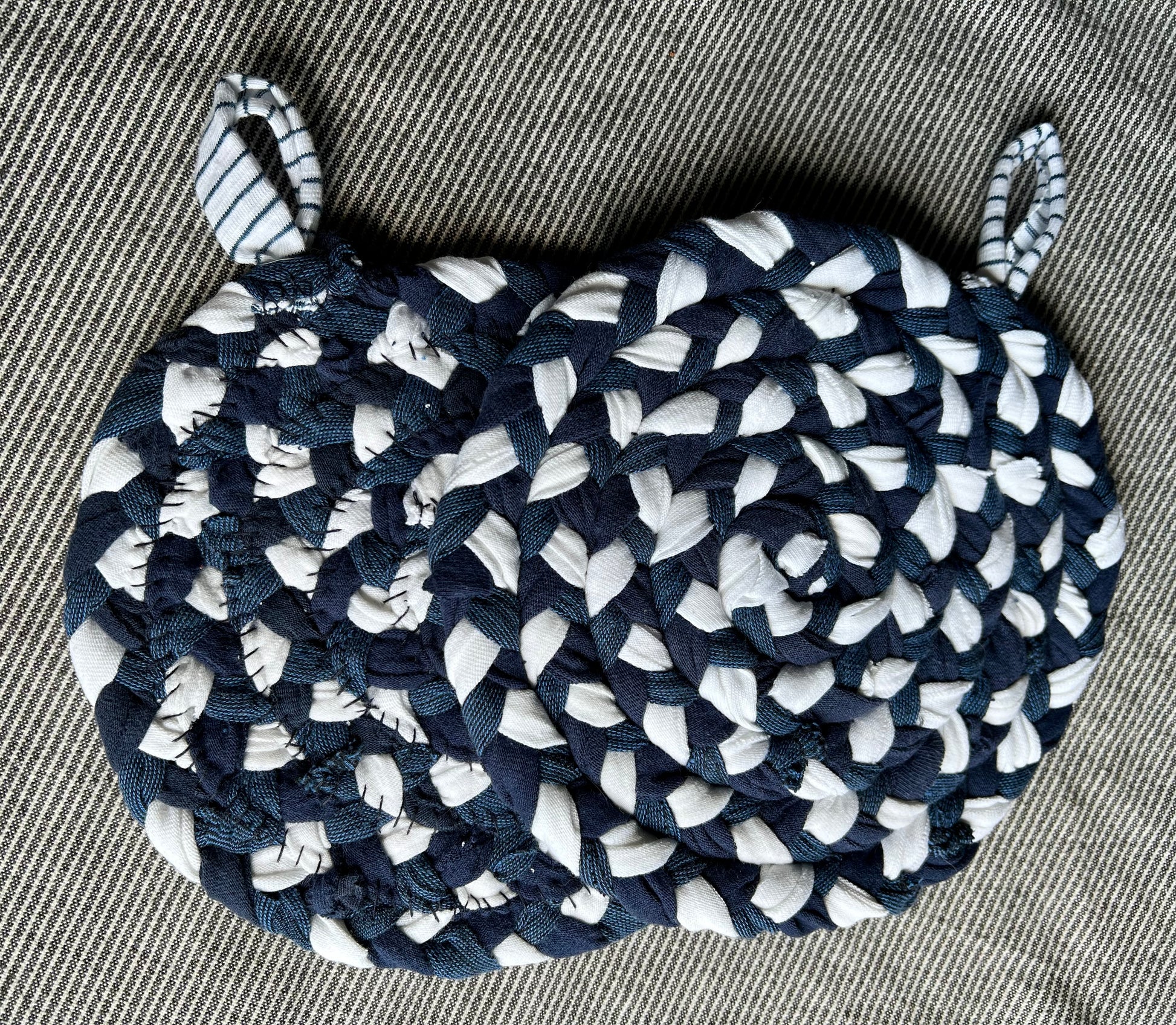 A set of two trivet potholders, side by side, lay flat on a fabric surface.