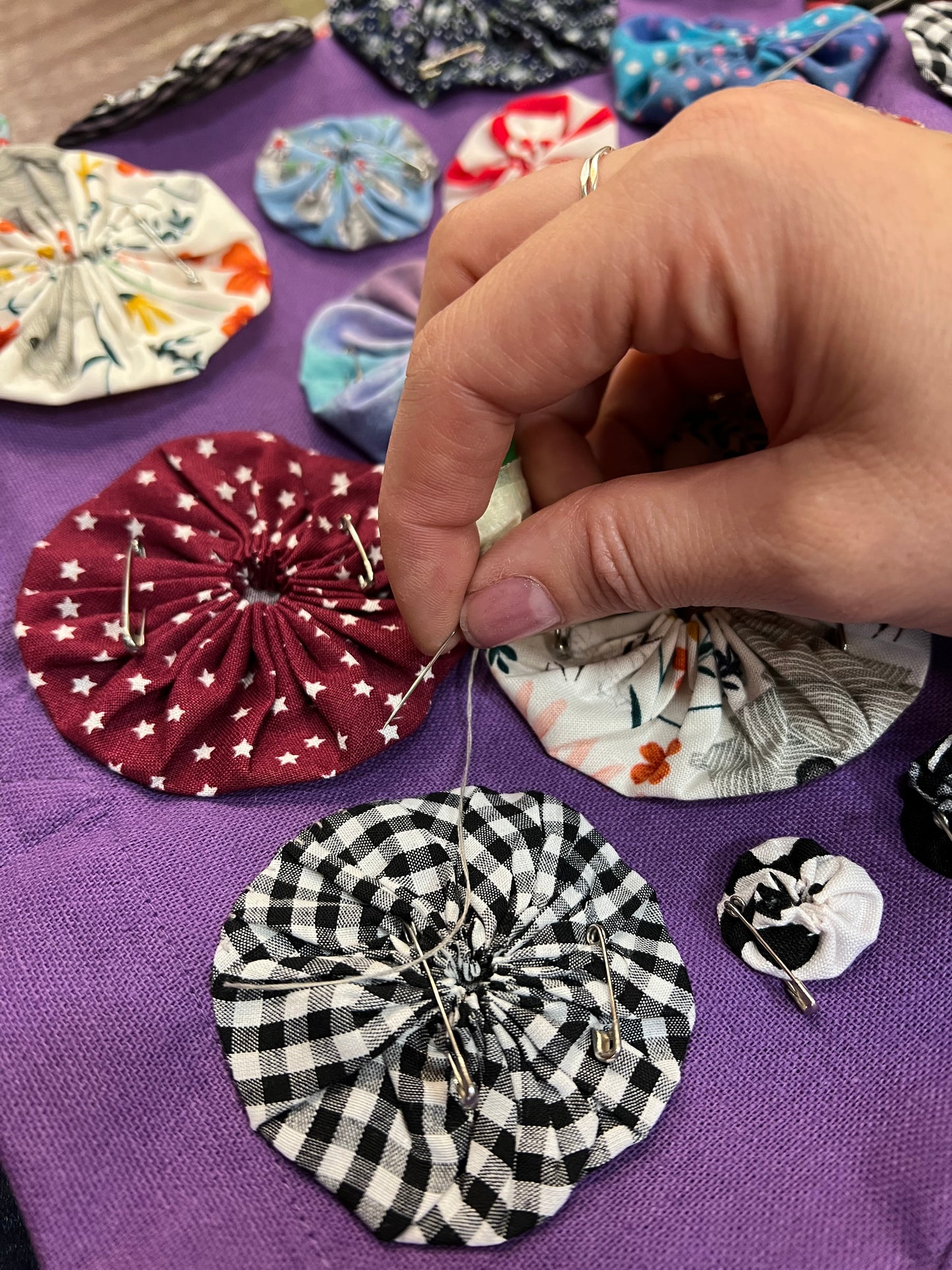 in progress shot of hand pulling needle through. each yoyo circle has been hand stitched down