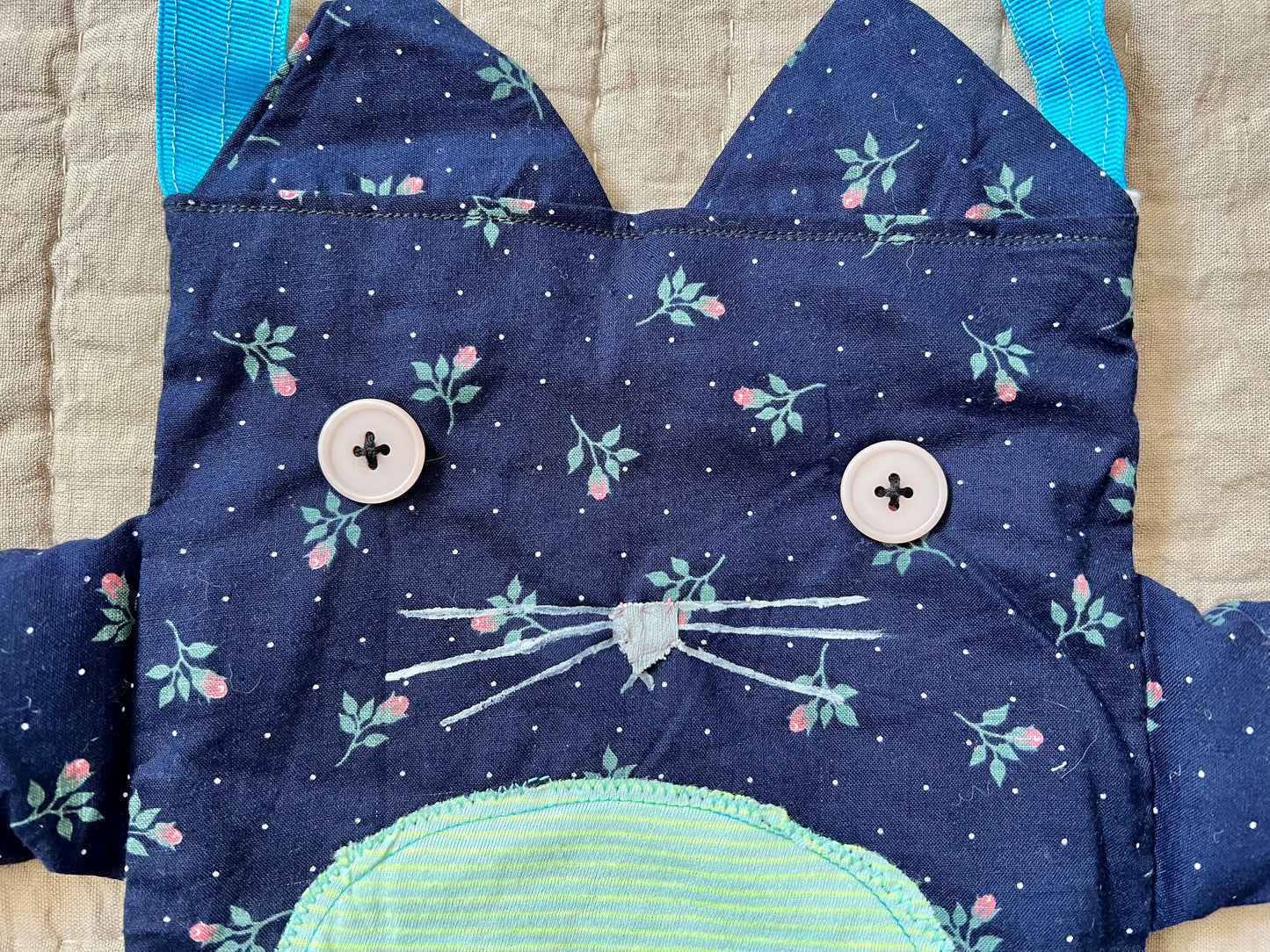 Closeup of kitty tote bag, showing off button eyes and hand-painted mouth and nose