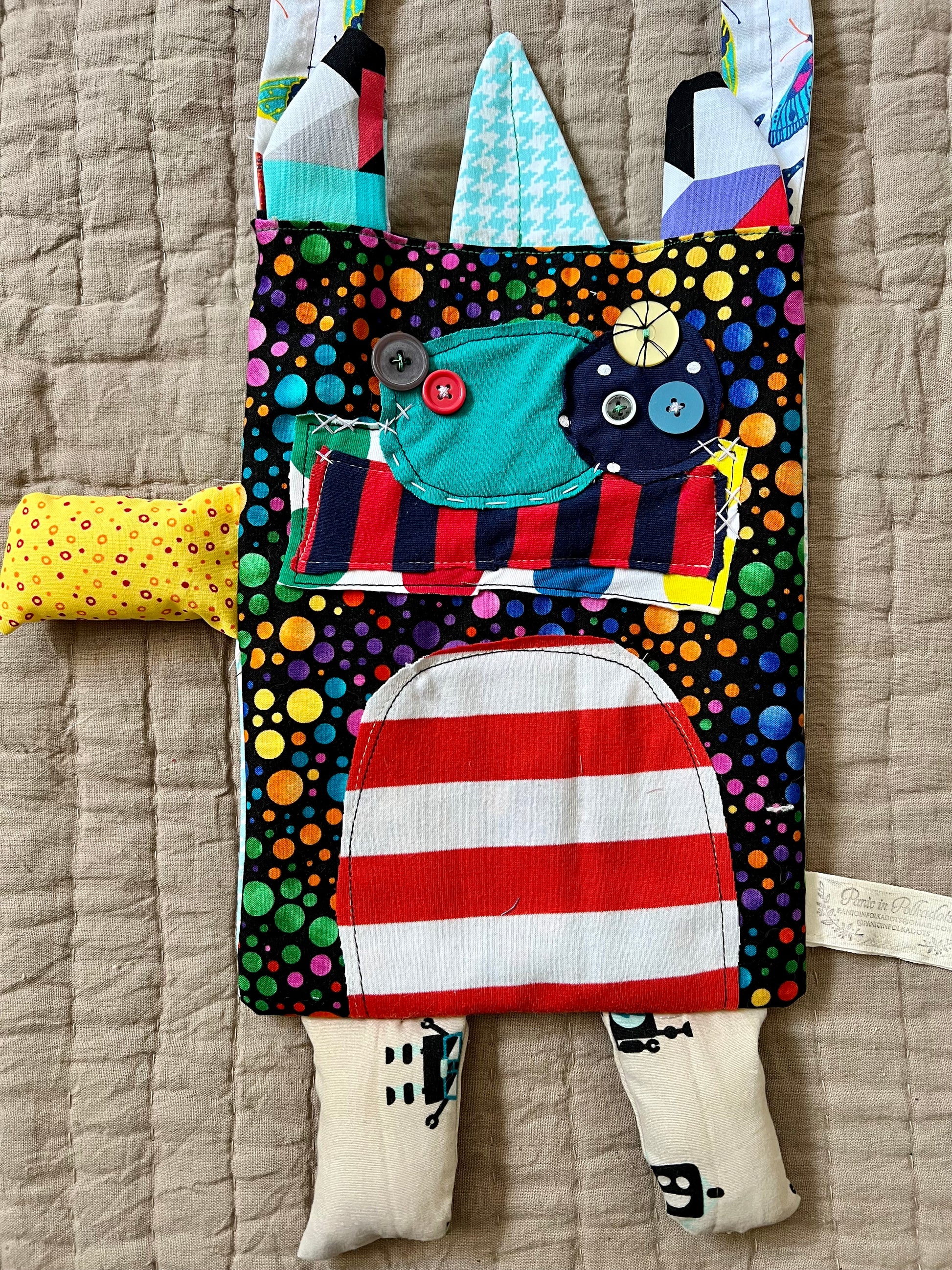 Monster tote bag. Body is bold bright polkadots, multiple button eyes, and a red and white striped tummy.