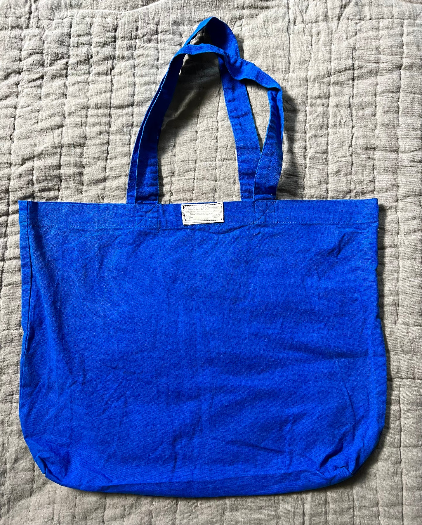 backview of blue tote bag, with Panic in Polkadots label