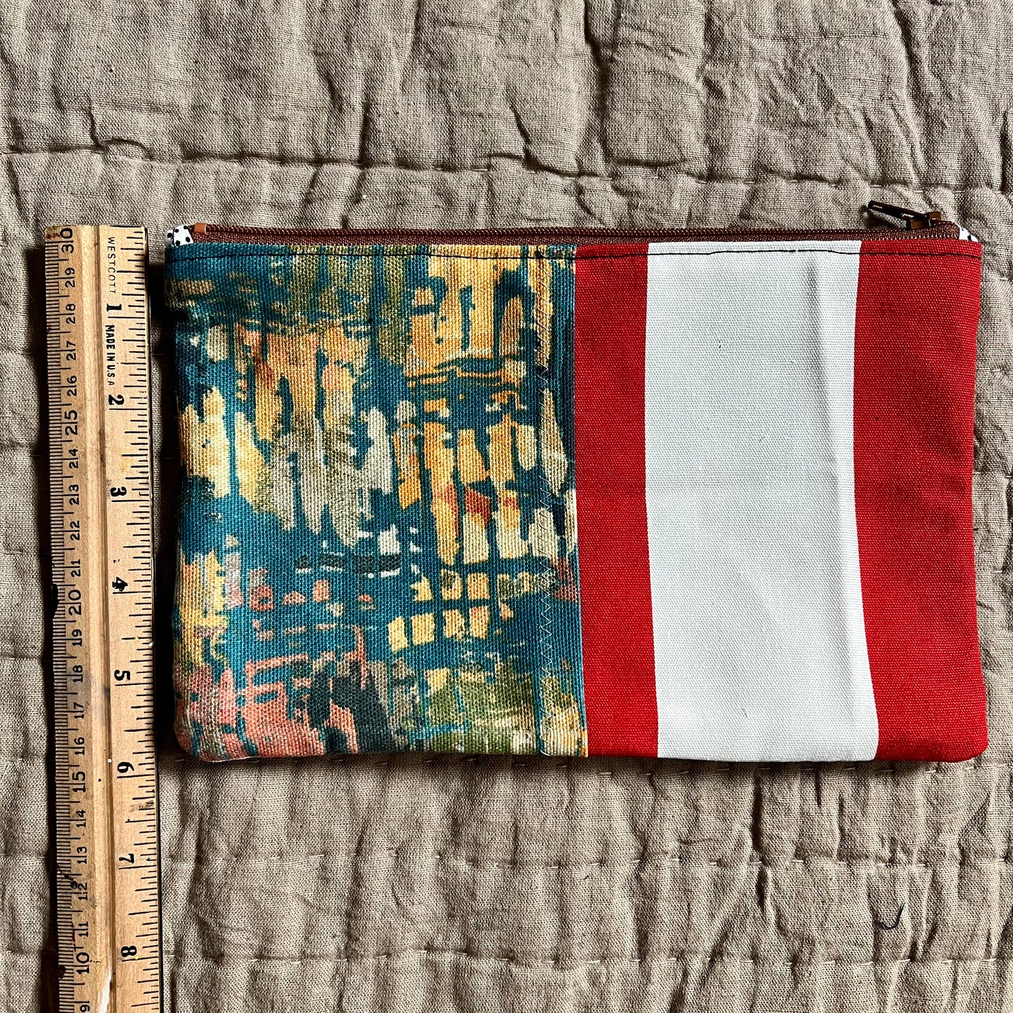 back of zipper pouch, with ruler on the side, showing about 6 inches in height.