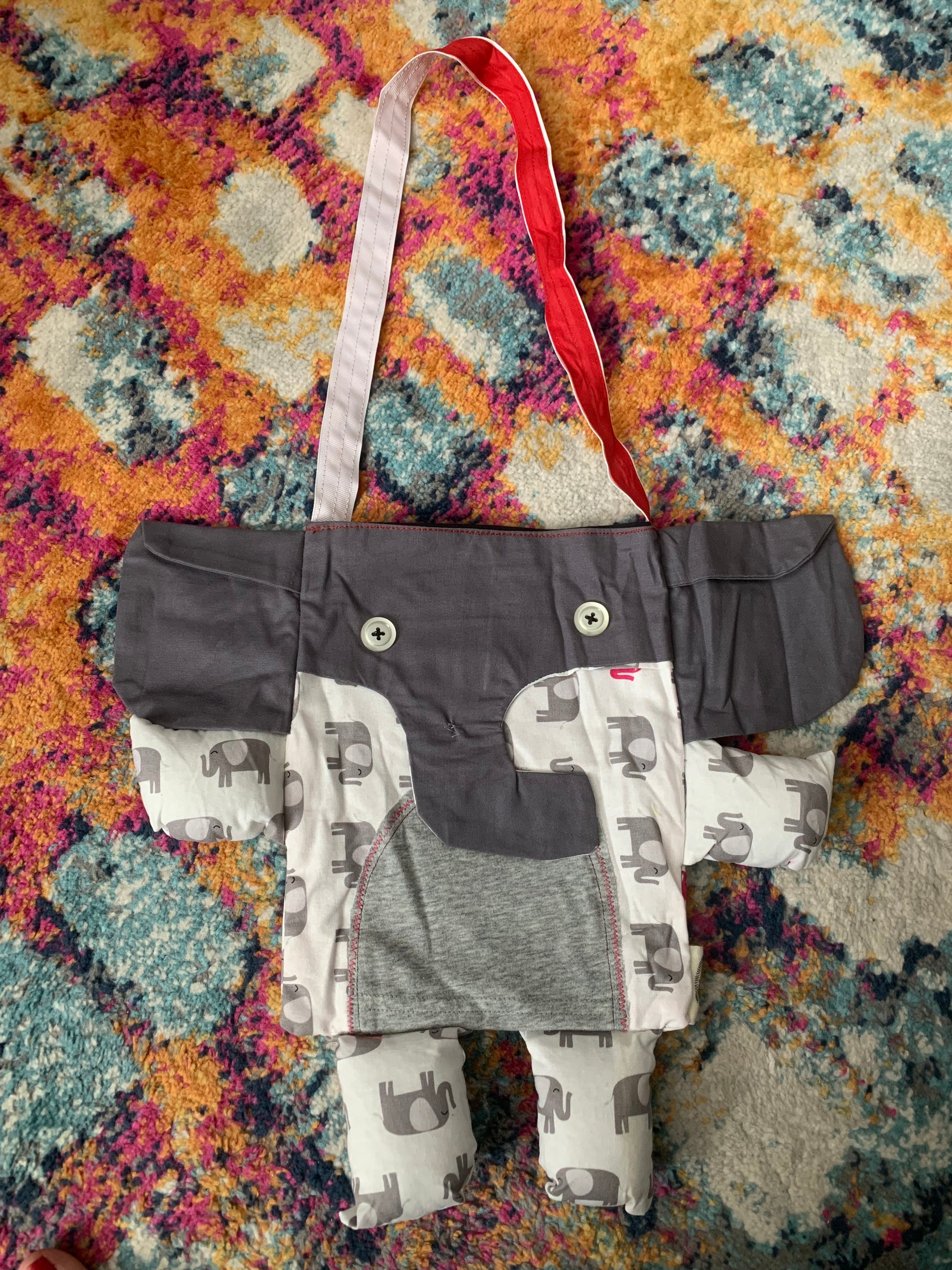 elephant tote bag, with red and white strap. Grey trunk and ears, navy floral print body, with baby elephant tummy.