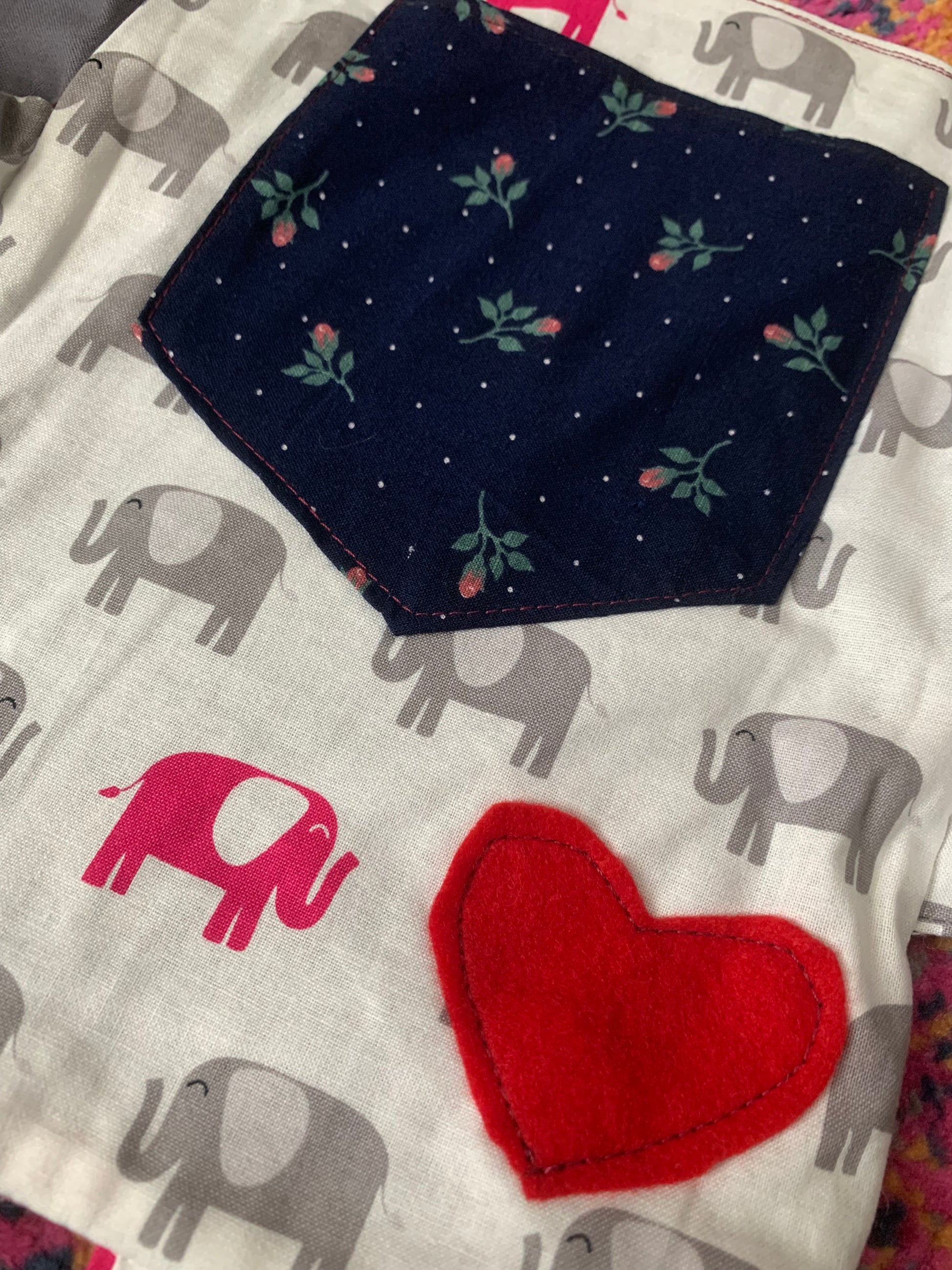 closeup of back of elephant tote bag, with a red heart and a navy floral pocket.