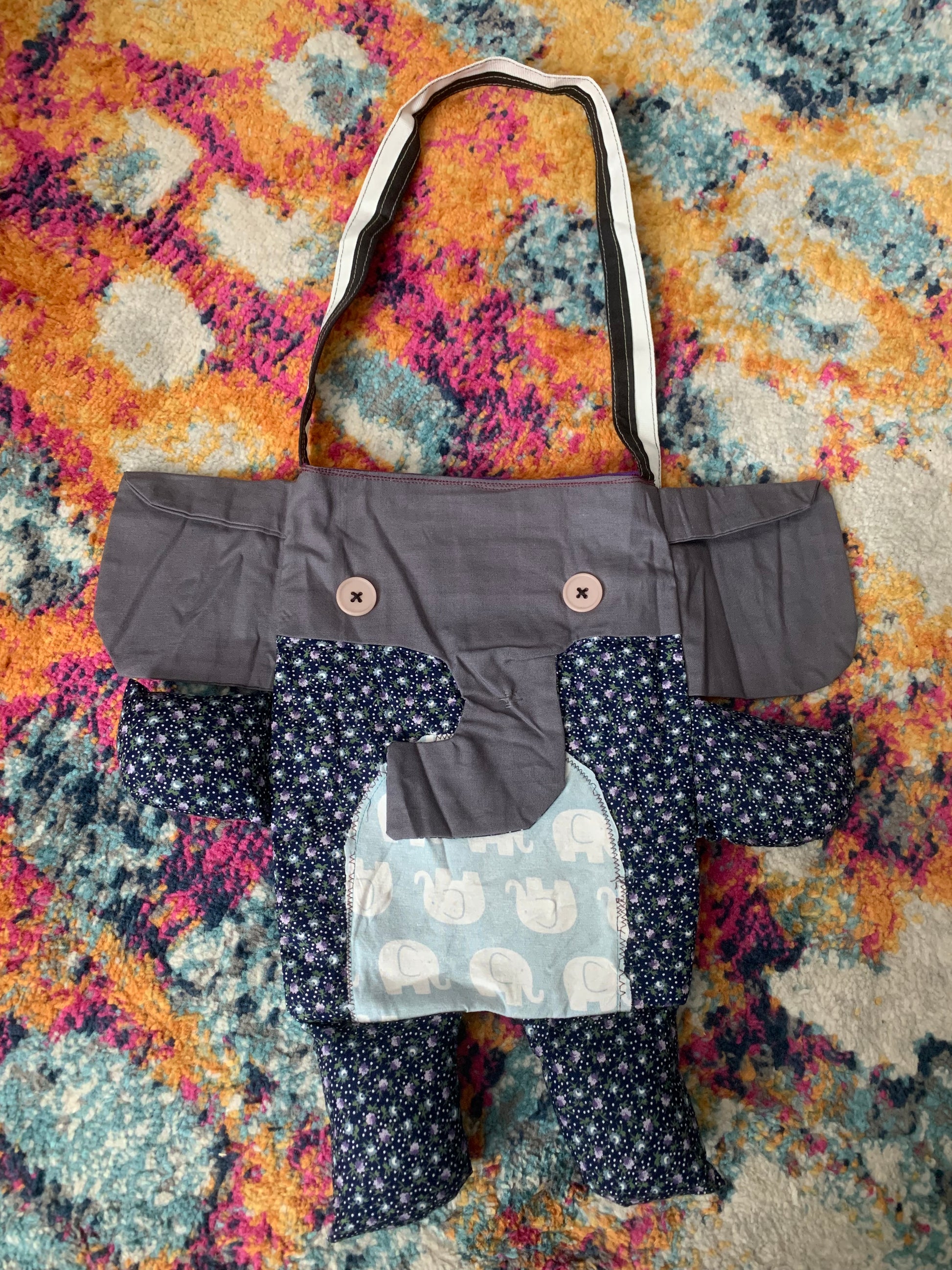 elephant tote bag, with black and white strap. Grey trunk and ears, navy floral print body, with baby elephant tummy.