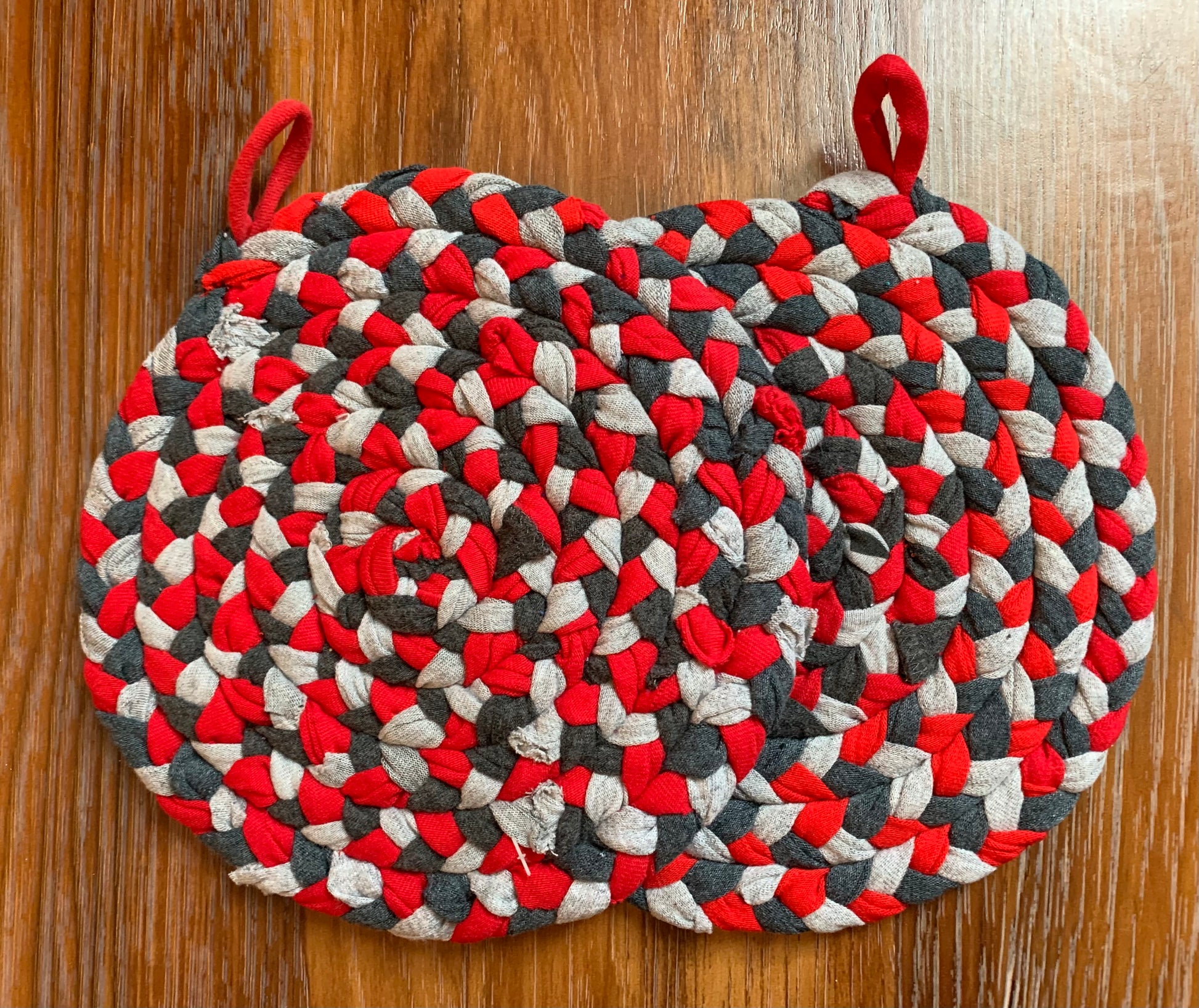 A set of two trivet potholders, side by side, lay flat on a wood surface.