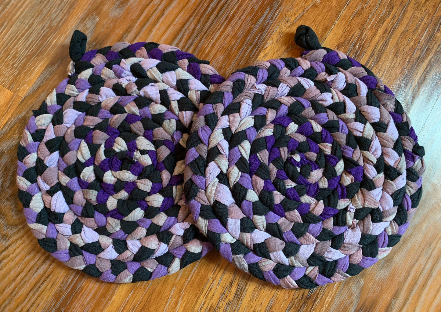 A set of two trivet potholders, side by side, lay flat on a wood surface.