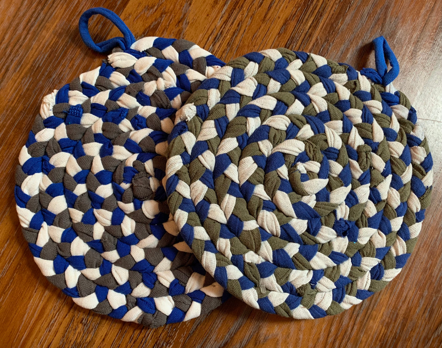 A set of two trivet potholders, side by side, lay flat on a wood surface.