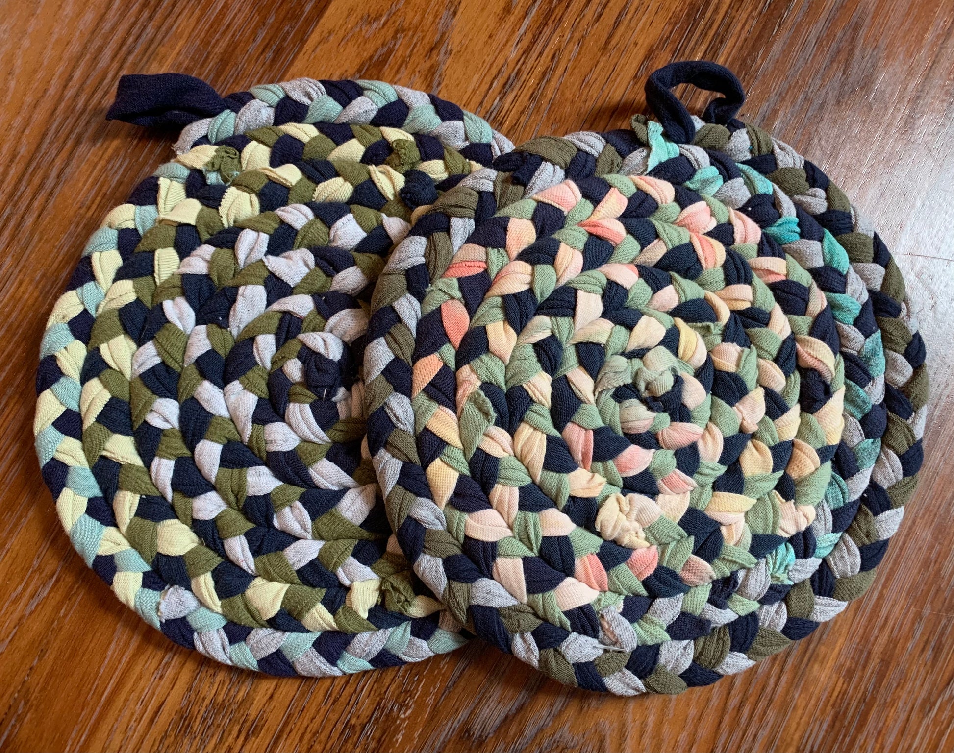 A set of two trivet potholders, side by side, lay flat on a wood surface.