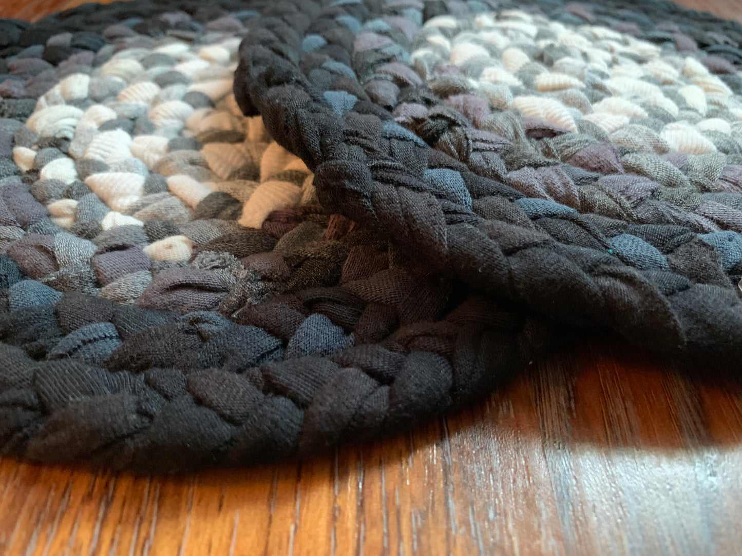 Side view of two trivet potholders, lay flat on a wood surface.