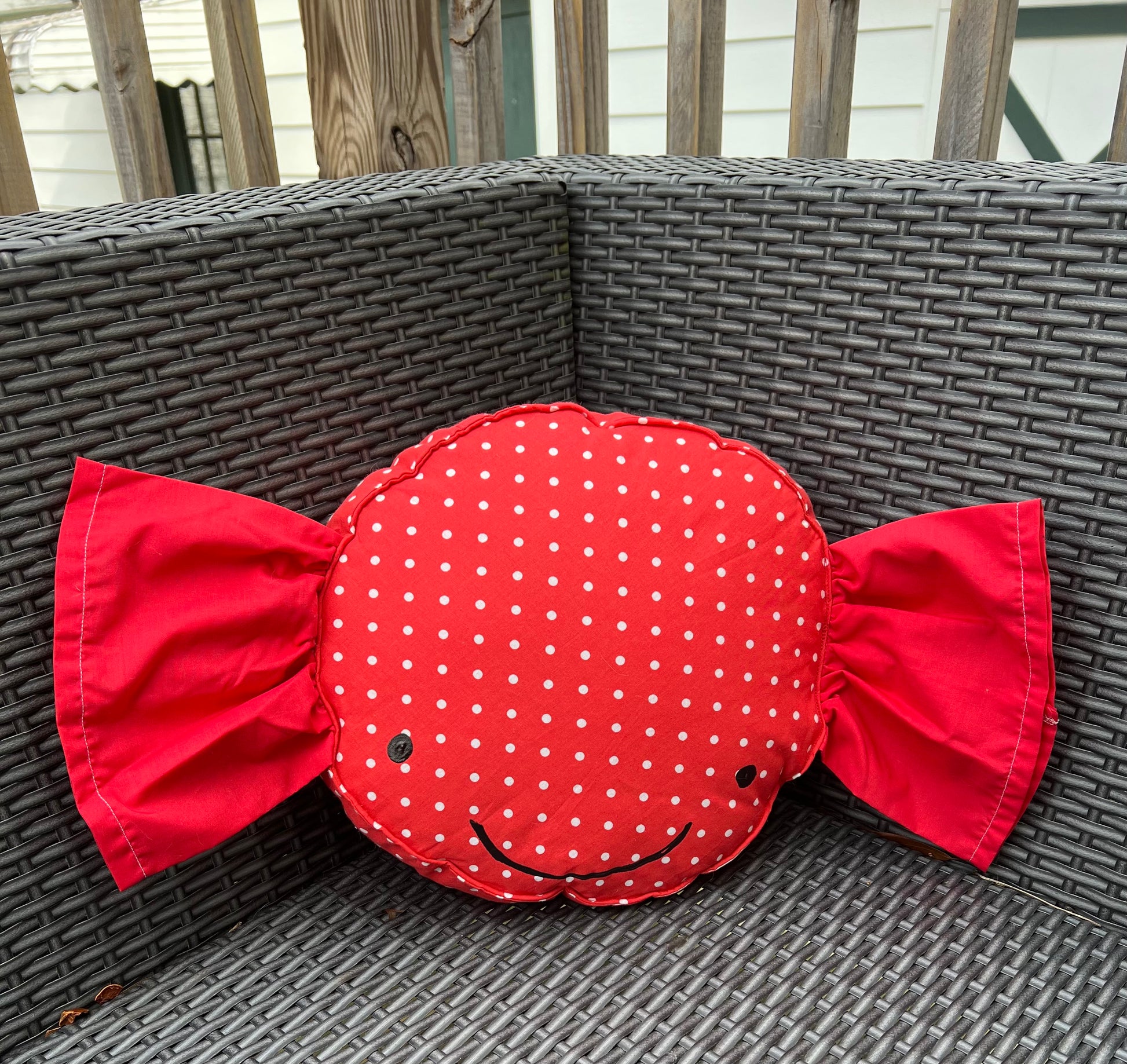 cute candy pillow, nestled in the corner of an outdoor patio chair.