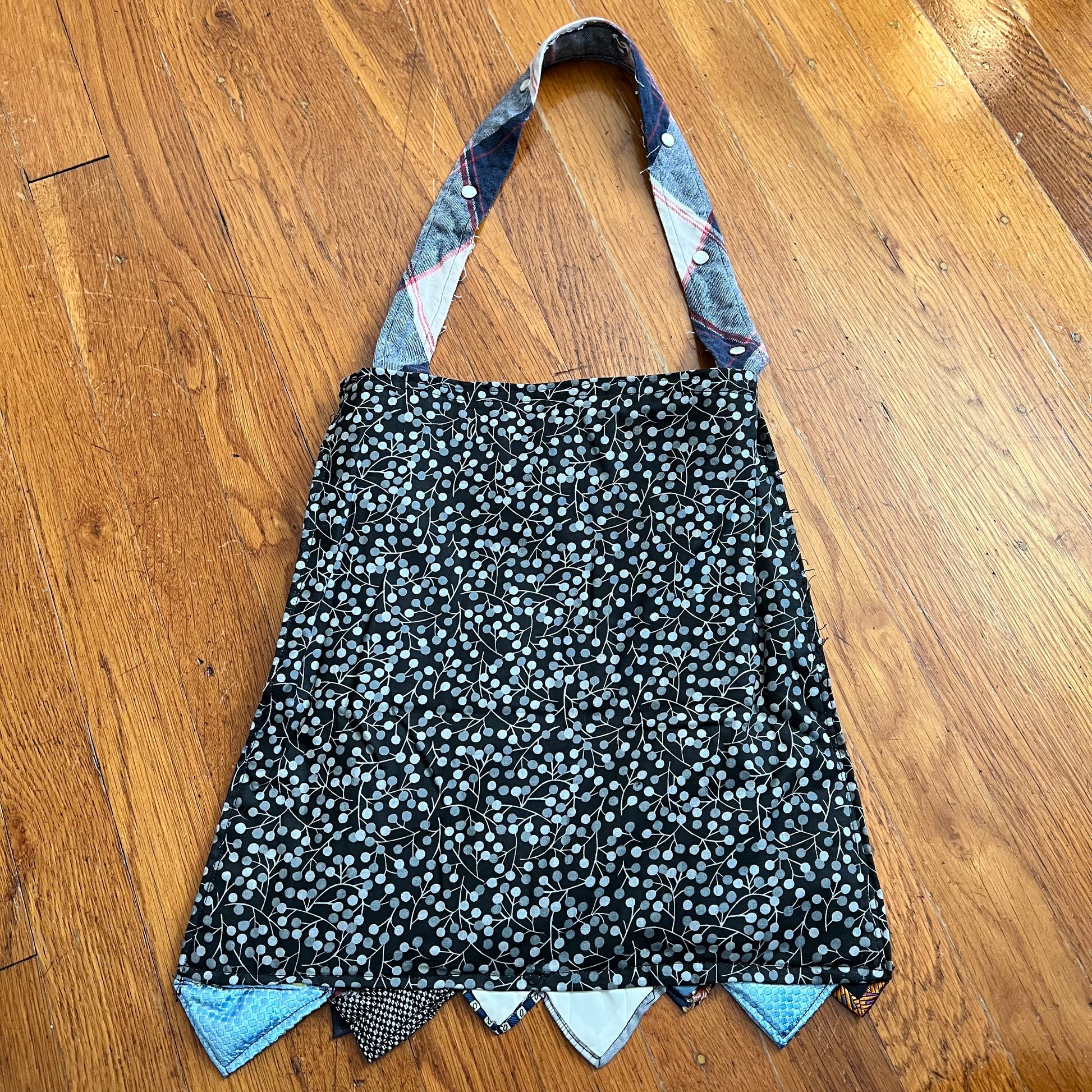 aerial back view of the teal tote bag, in a dotty black floral material against a wood background