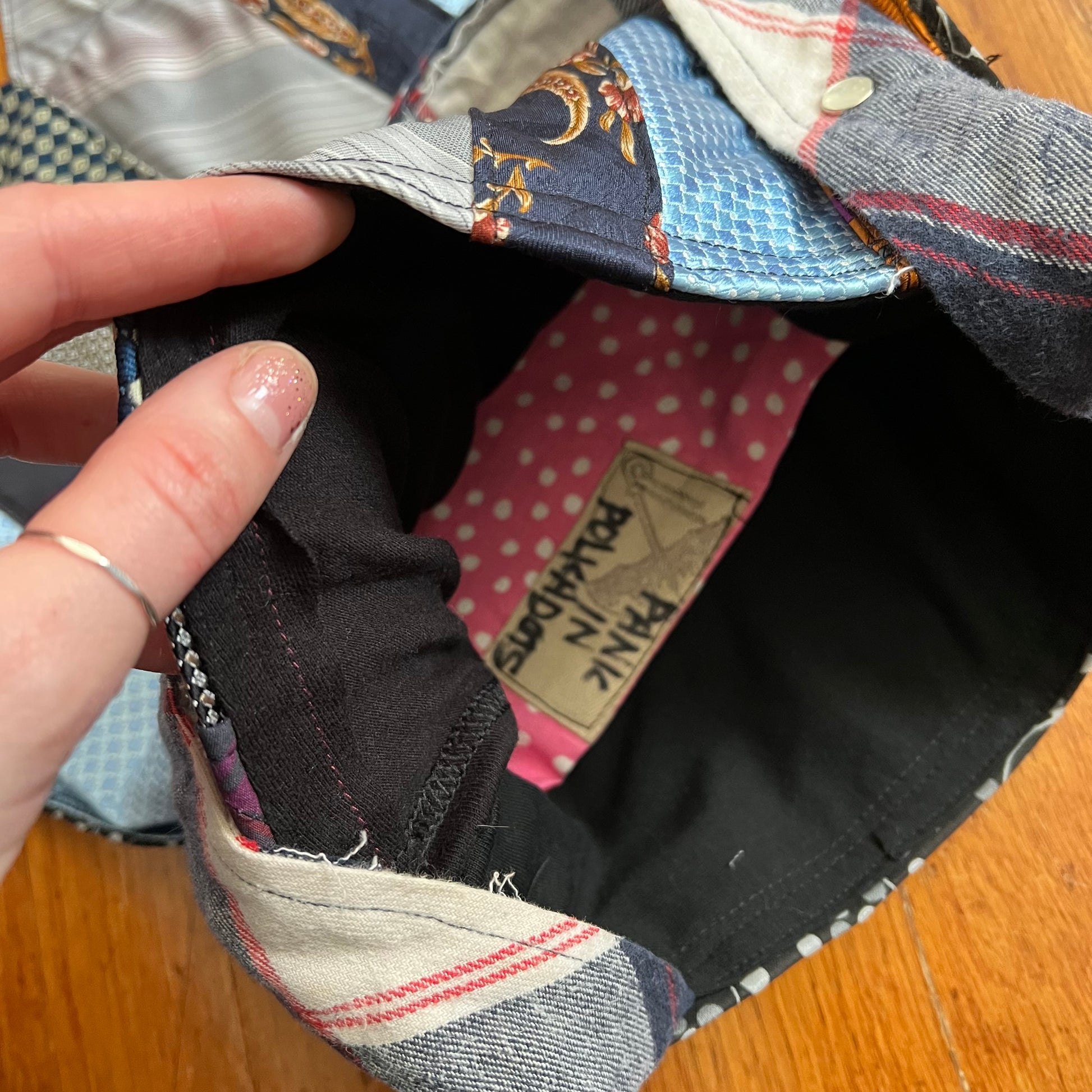 Inside of tote bag, showing a soft tshirt interior with a pink polkadots pocket. Panic in Polkadots label.