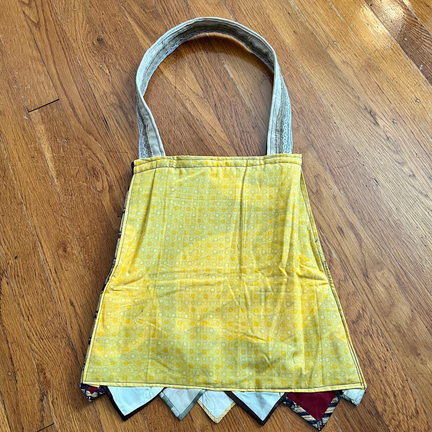 aerial back view of the teal tote bag, in a yellow dot material against a wood background