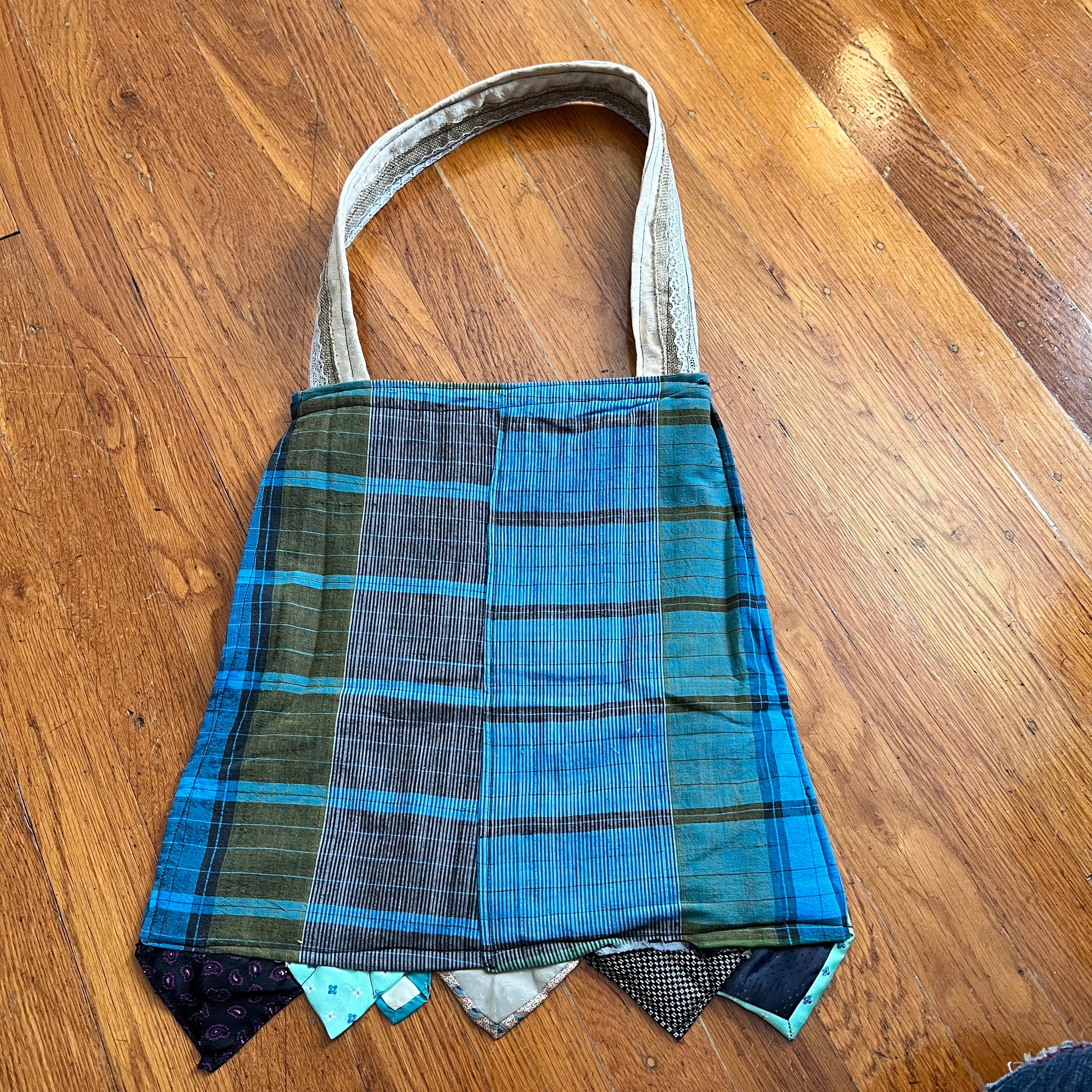 aerial back view of the teal tote bag, in a plaid material against a wood background