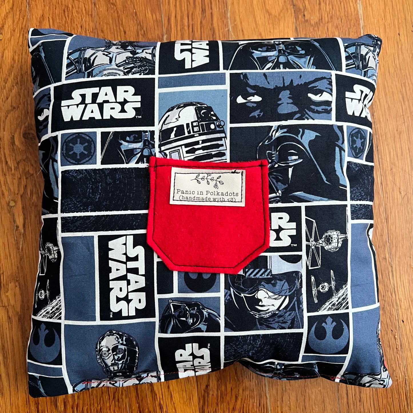 back view of pillow, with star wars print, and a felt red pocket with Panic label