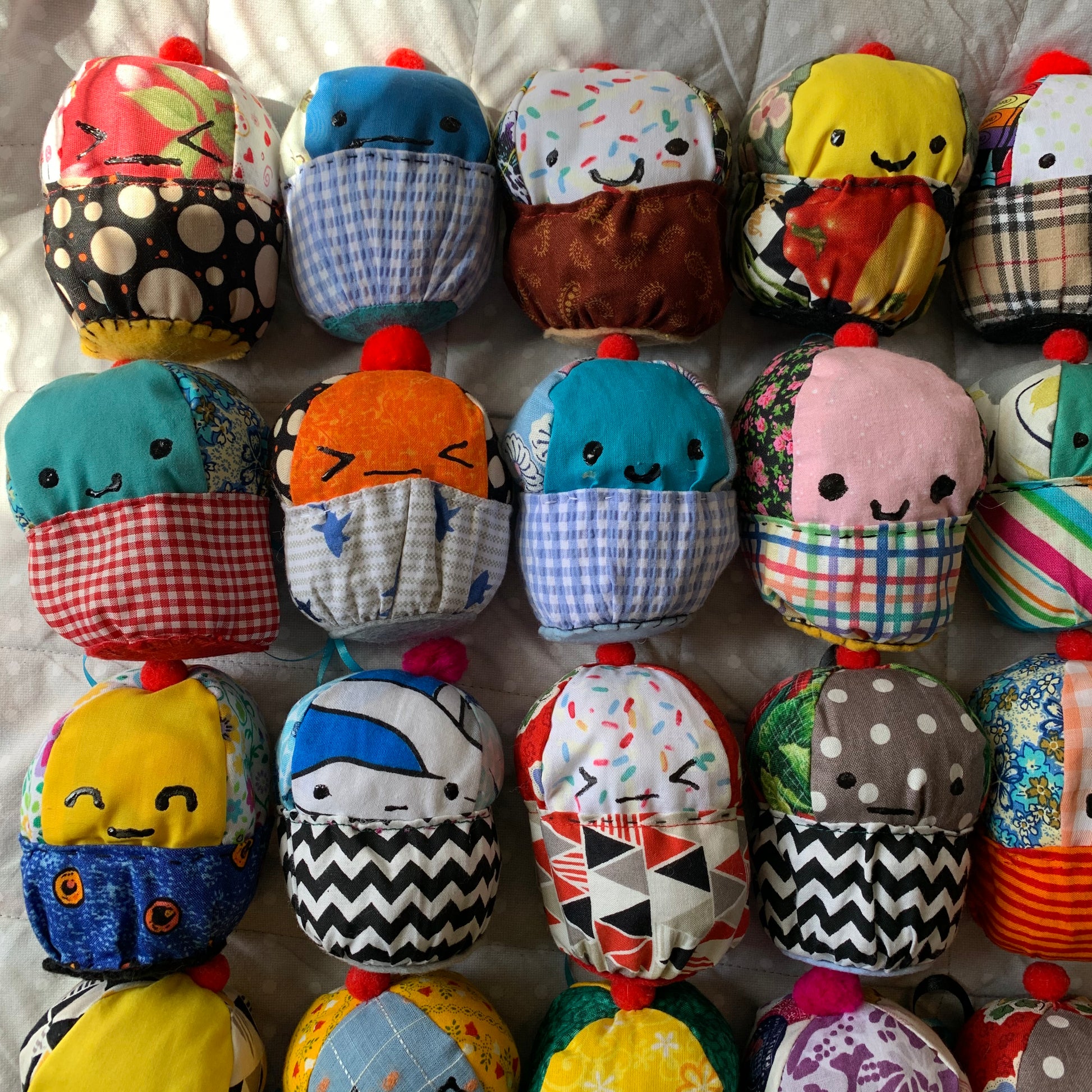 A closer view of colorful plush cupcakes with various facial expressions. Set up in a square formation.