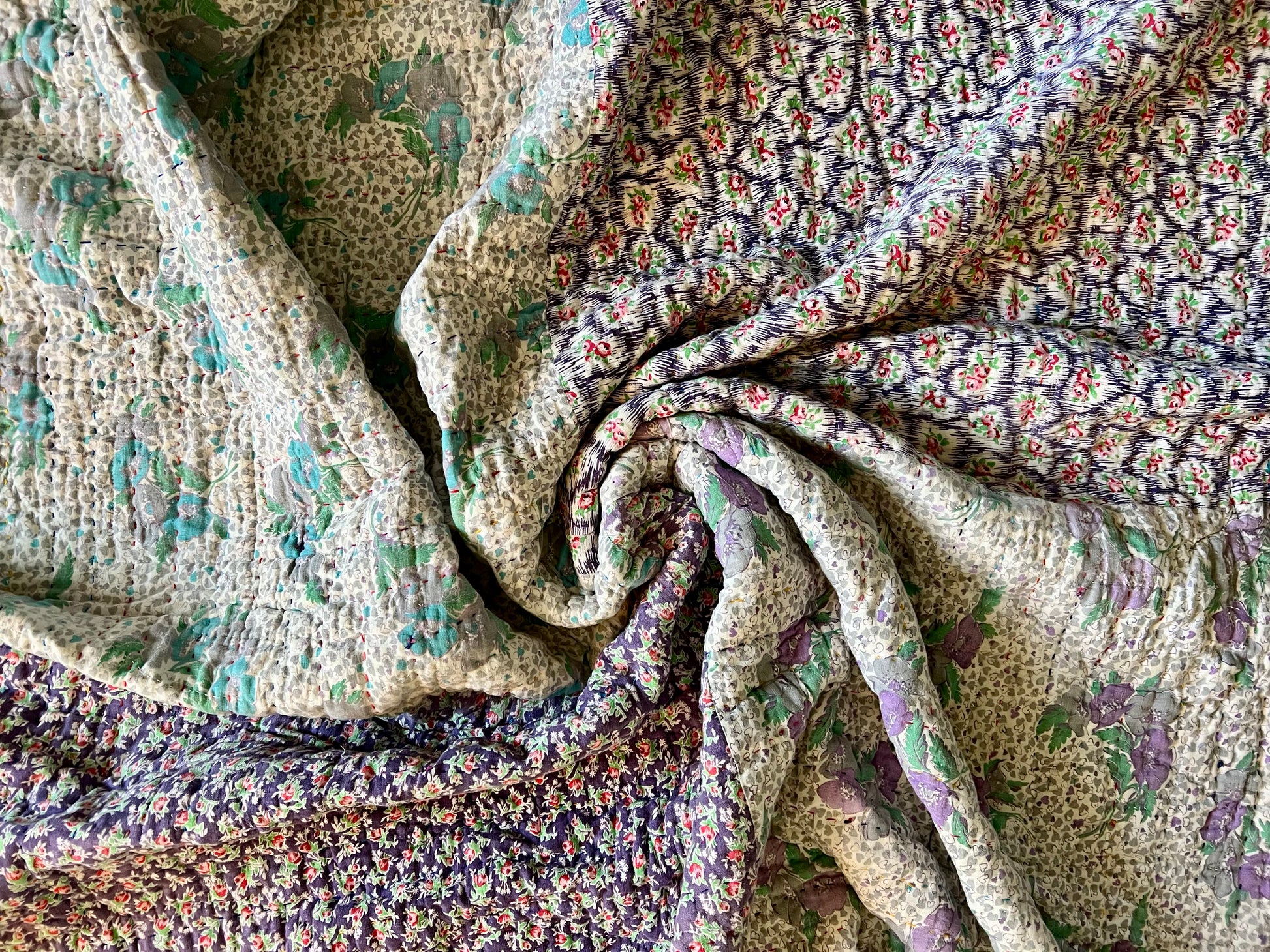 Kantha hand-stitched vintage feedsack quilt. spiral aerial view of the back of quilt