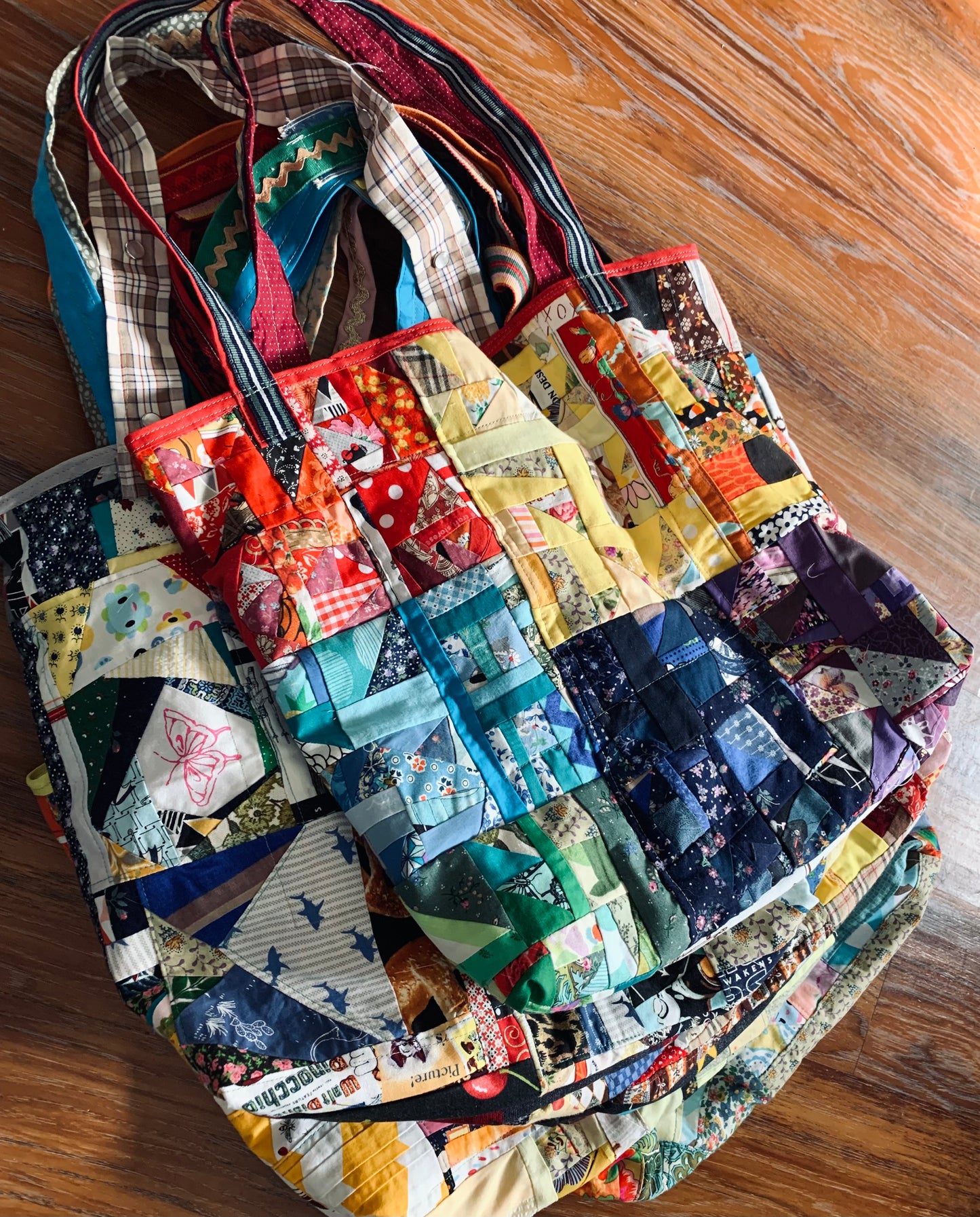 stack of colorful perfectly imperfect tote bags on a wood background