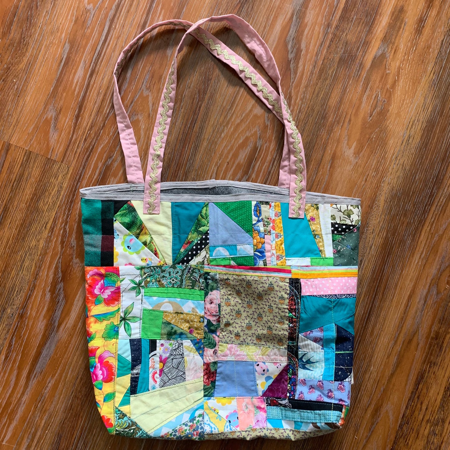 aerial view of green pink collage tote bag, on a wood floor background