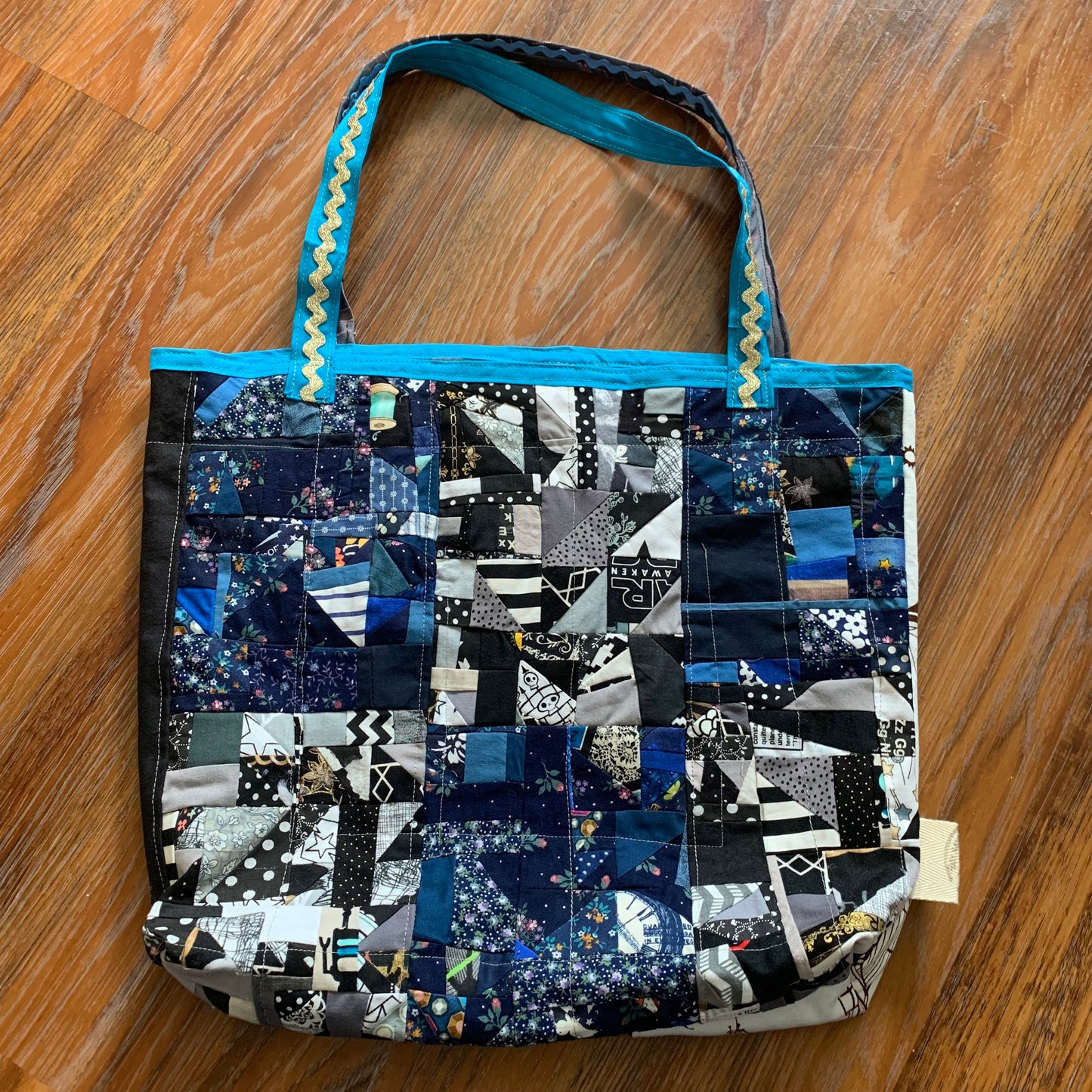 aerial view of blue black collage tote bag, on a wood floor background