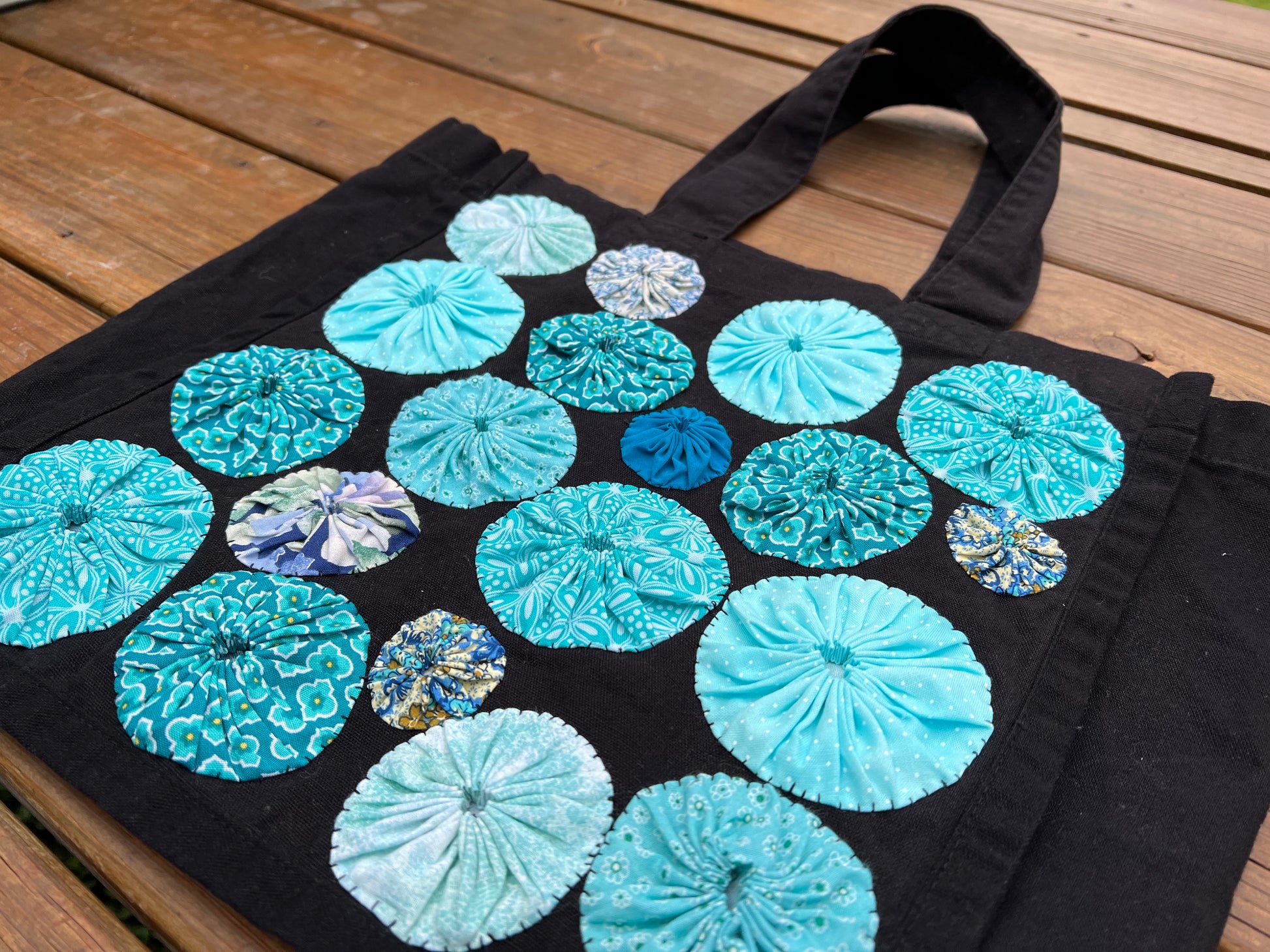 side view closeup of black tote bag against a wood background